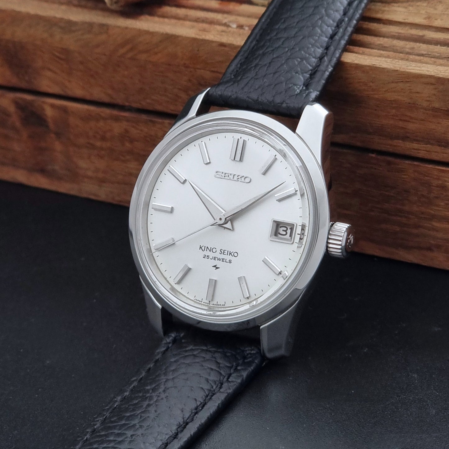 Vintage King Seiko 4402-8000 Wristwatch with a white dial on a dark background crown view