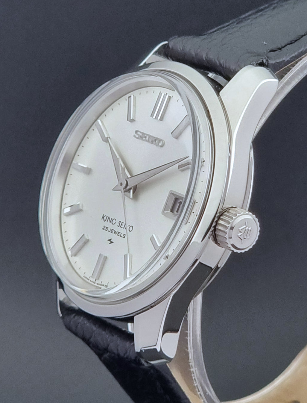 Vintage King Seiko Wristwatch 4402-8000 on a black leather strap on a dark background crown side
