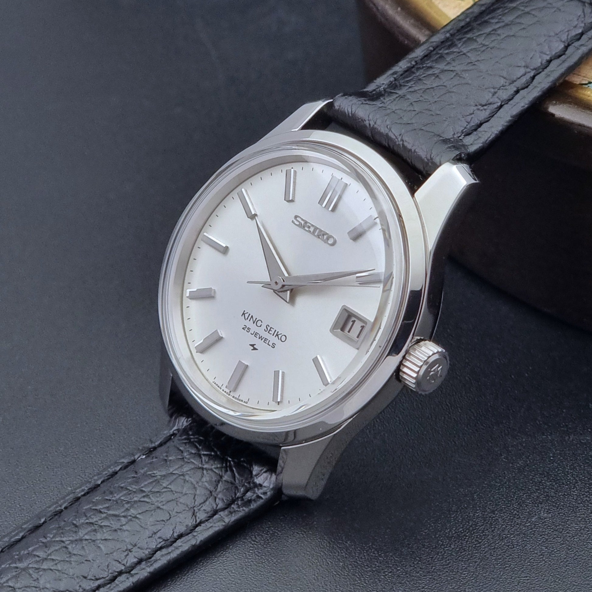 Vintage King Seiko Wristwatch 4402-8000 on a black leather strap on a dark background crown side view
