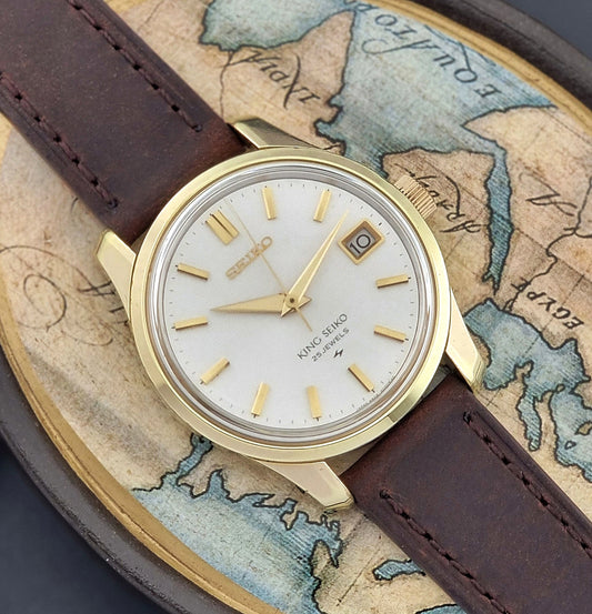 Vintage King Seiko 4402-8000 wristwatch with brown leather strap and gold case on a world map background