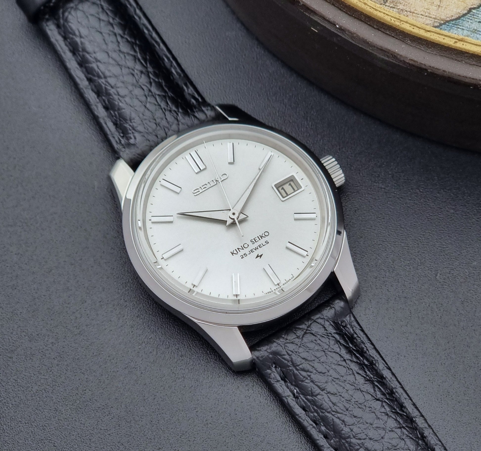 Vintage King Seiko Wristwatch 4402-8000 on a black leather strap on a dark background