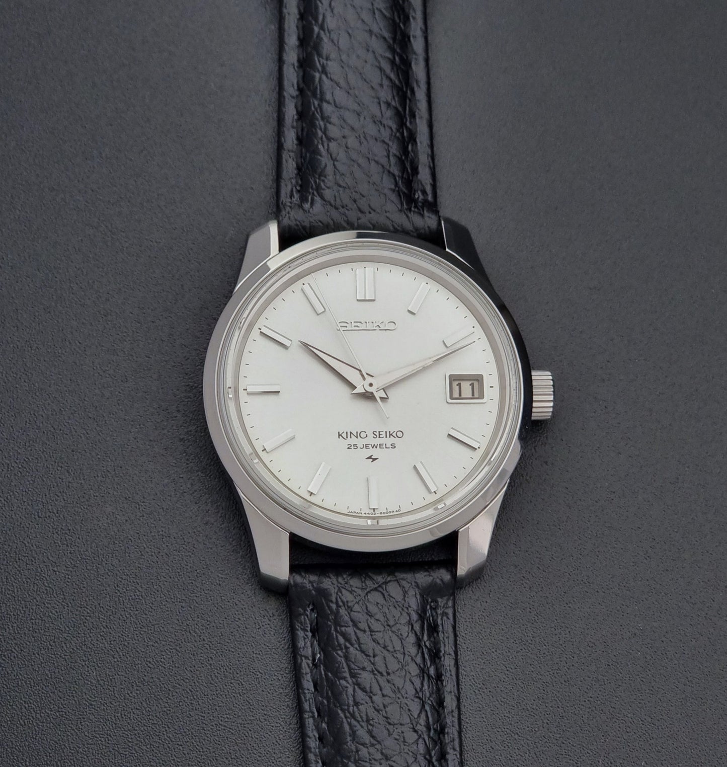 Vintage King Seiko Wristwatch 4402-8000 on a black leather strap on a dark background front view