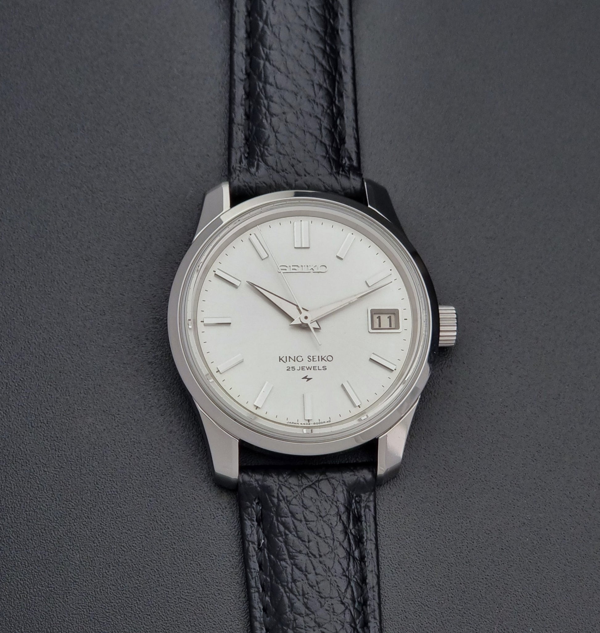 Vintage King Seiko Wristwatch 4402-8000 on a black leather strap on a dark background front view