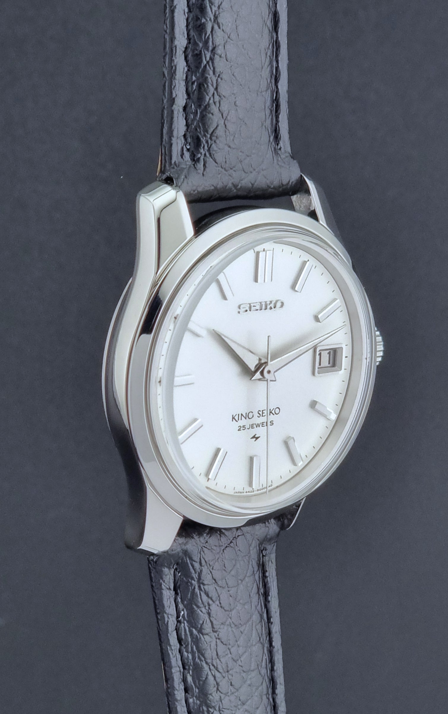 Vintage King Seiko Wristwatch 4402-8000 on a black leather strap on a dark background profile view