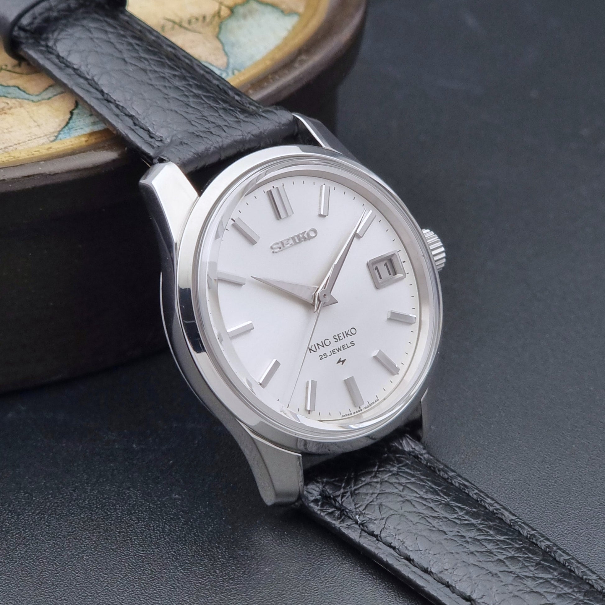 Vintage King Seiko Wristwatch 4402-8000 on a black leather strap on a dark background side view