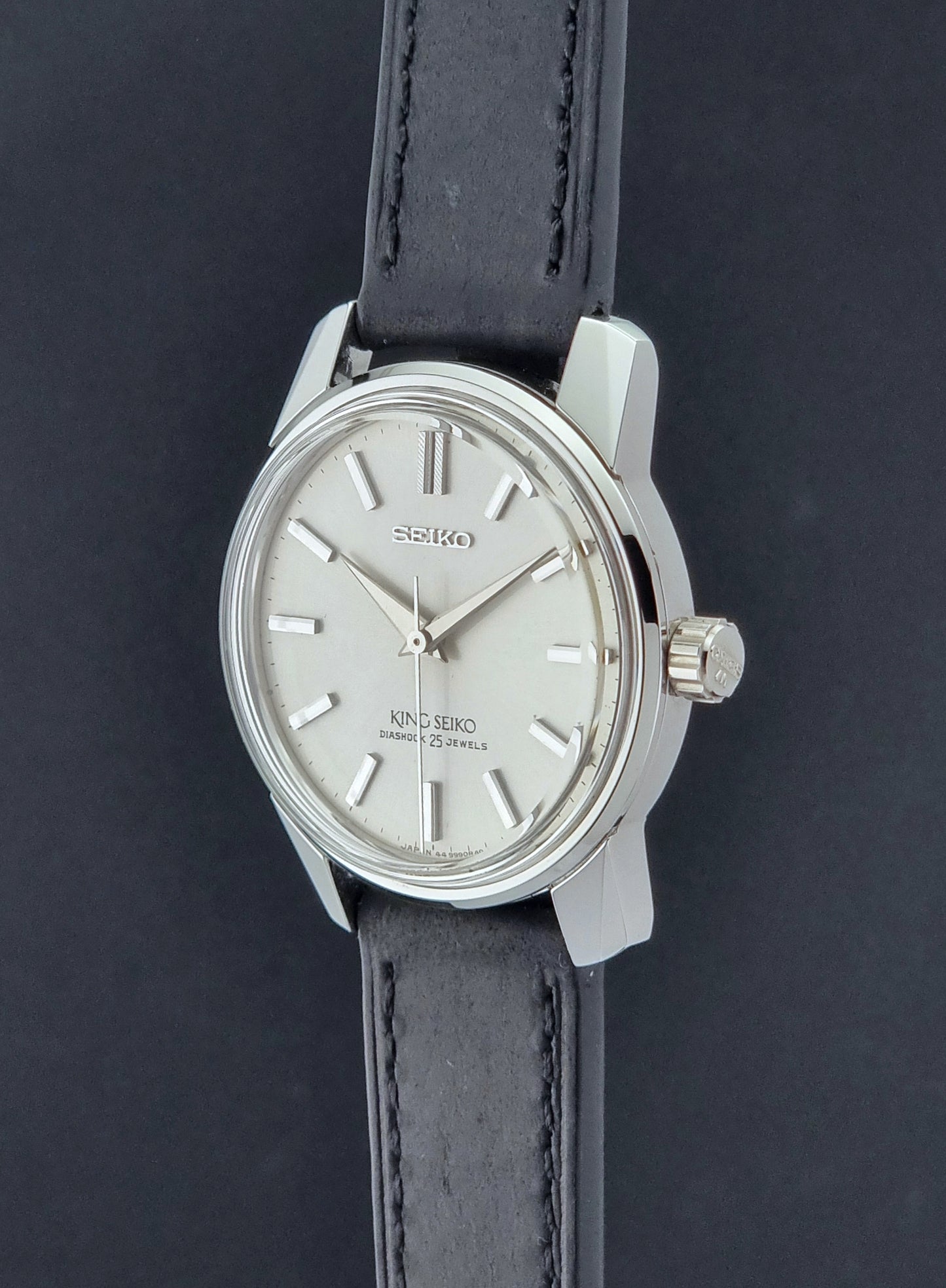 Vintage King Seiko Wristwatch 44999  with a black leather strap on a dark surface crown profile view