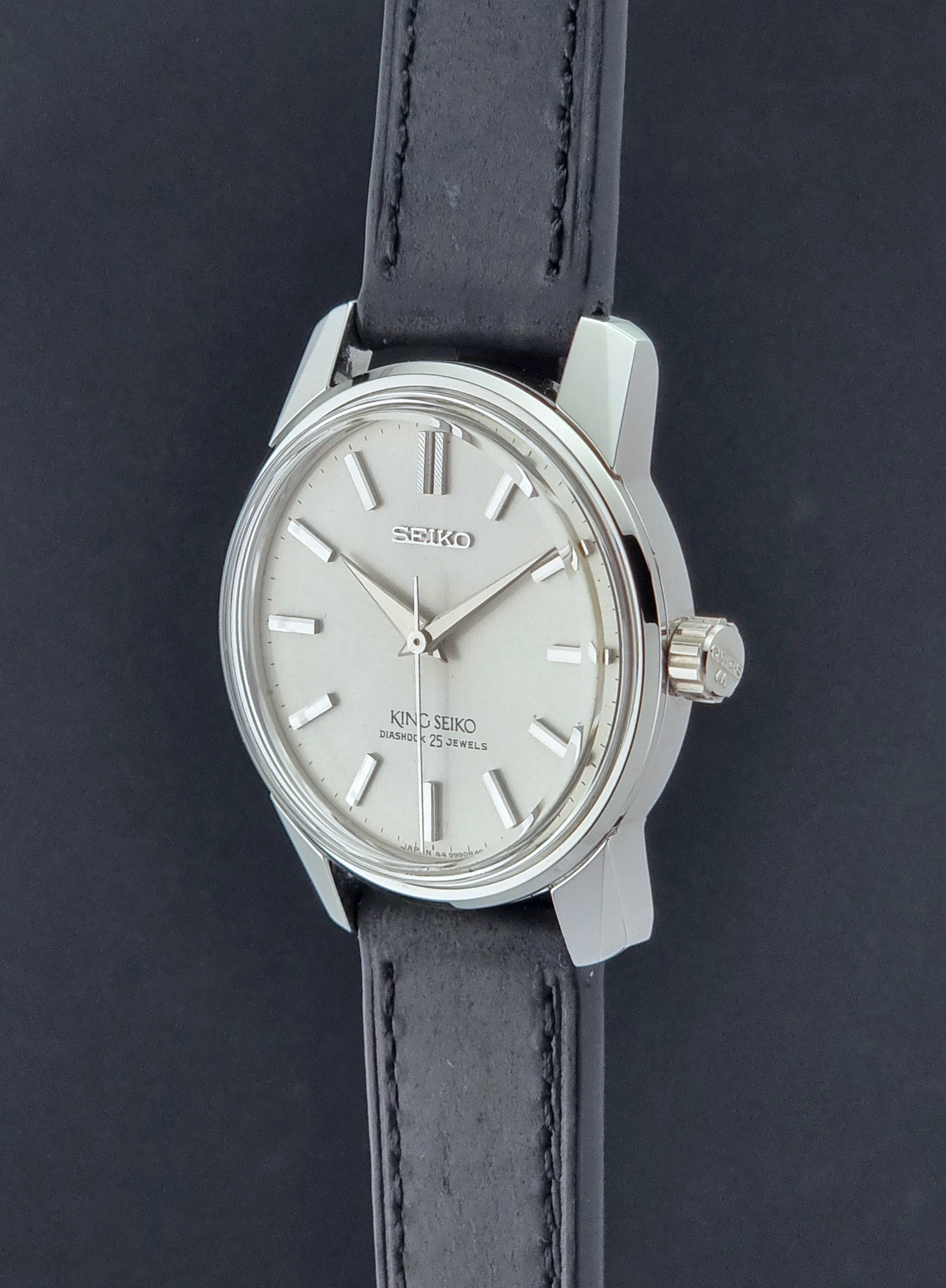 Vintage King Seiko Wristwatch 44999  with a black leather strap on a dark surface crown profile view