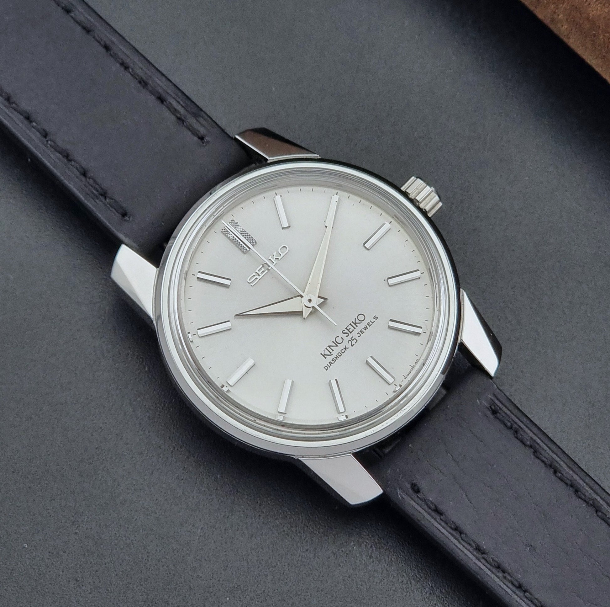 Vintage King Seiko Wristwatch 44999  with a black leather strap on a dark surface close up dial view