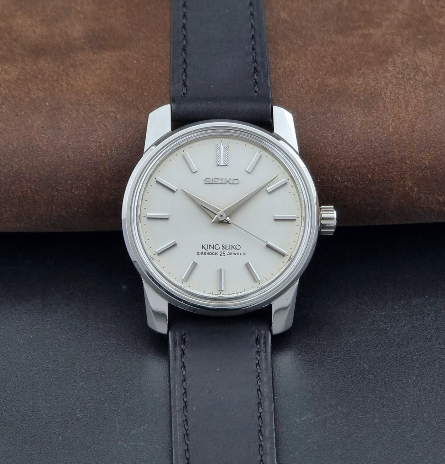 Vintage King Seiko Wristwatch 44999  with a black leather strap on a dark surface dial view