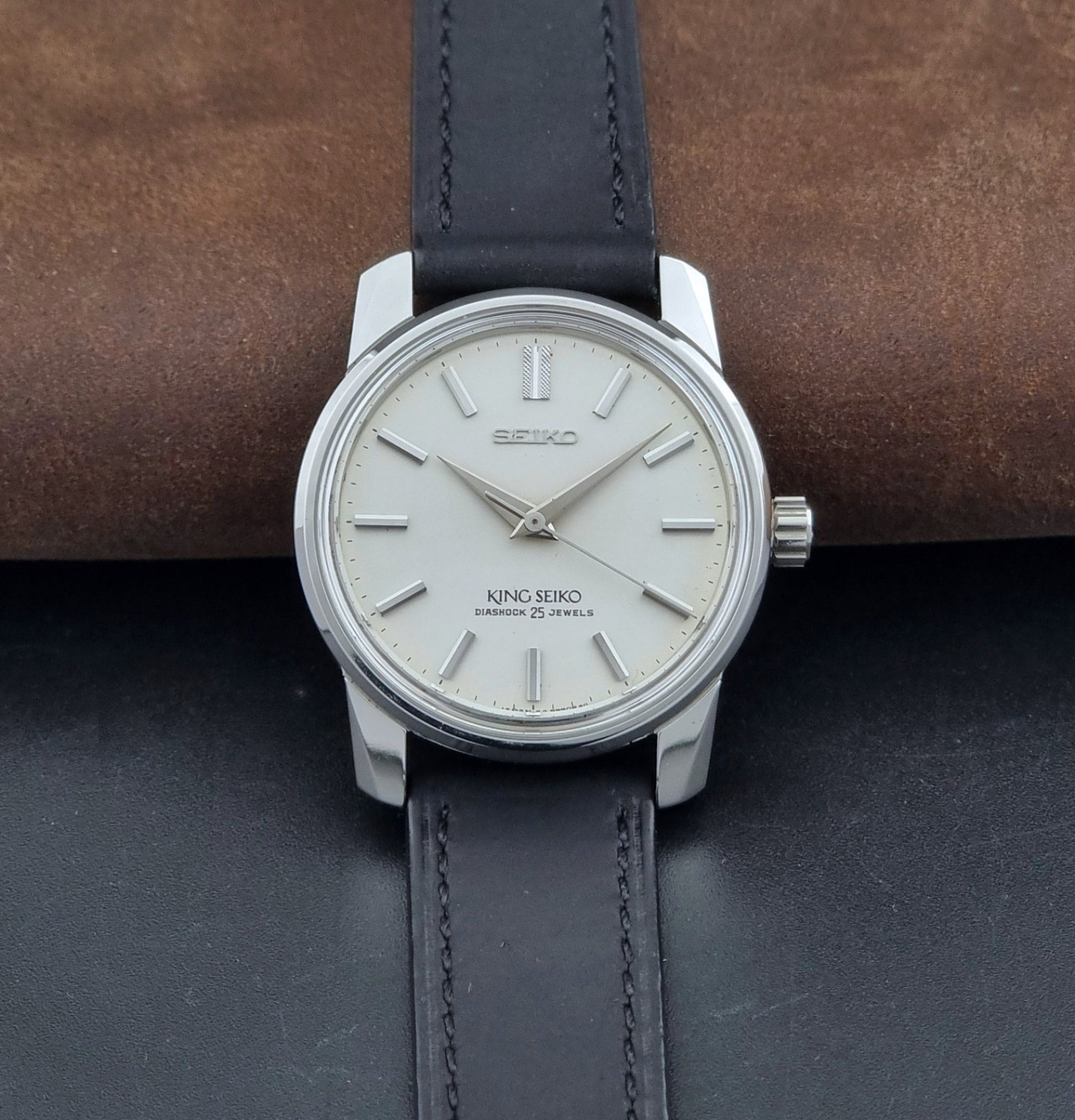 Vintage King Seiko Wristwatch 44999  with a black leather strap on a dark surface dial view