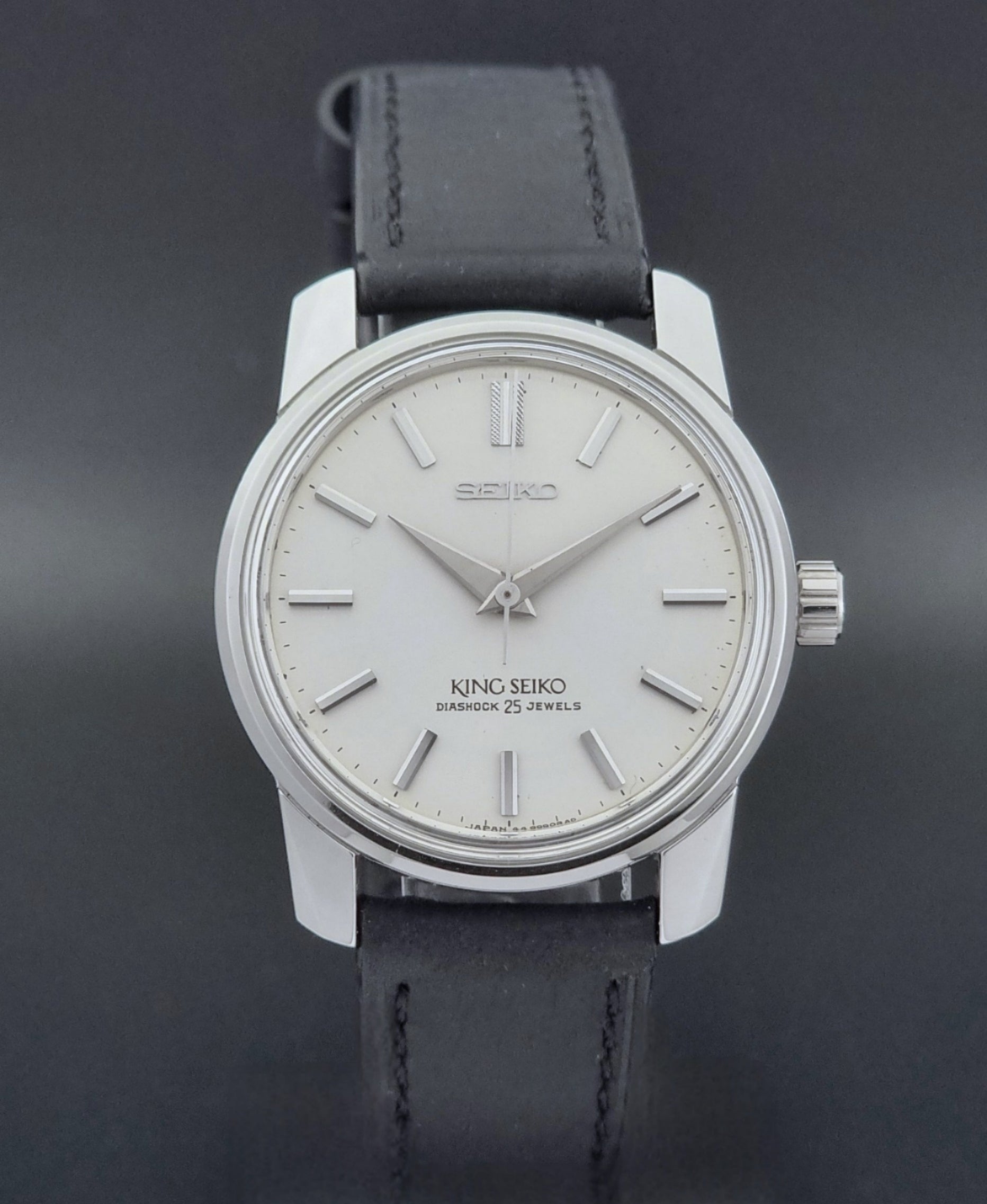 Vintage King Seiko Wristwatch 44999  with a black leather strap on a dark surface close dial view