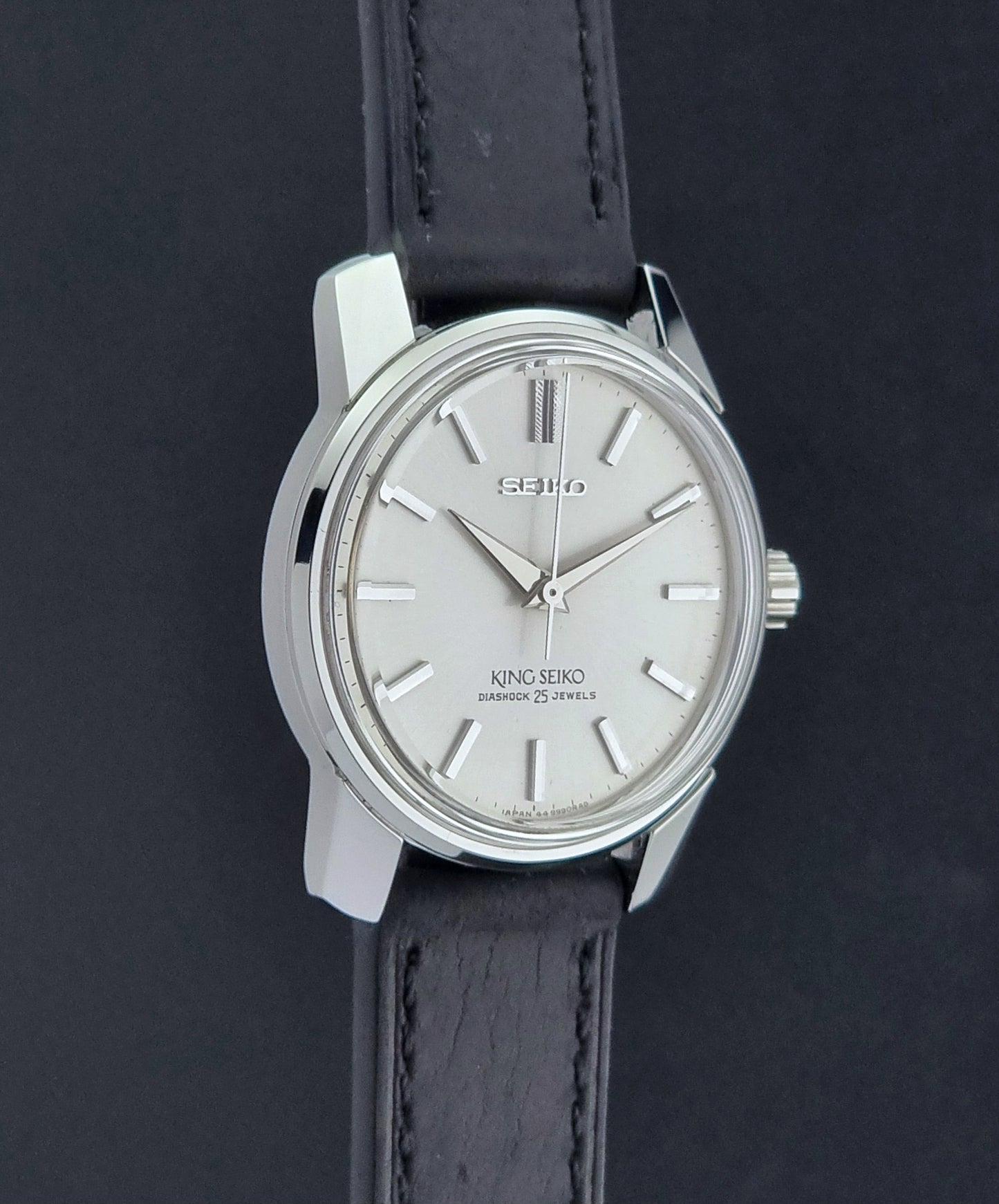 Vintage King Seiko Wristwatch 44999  with a black leather strap on a dark surface side profile view