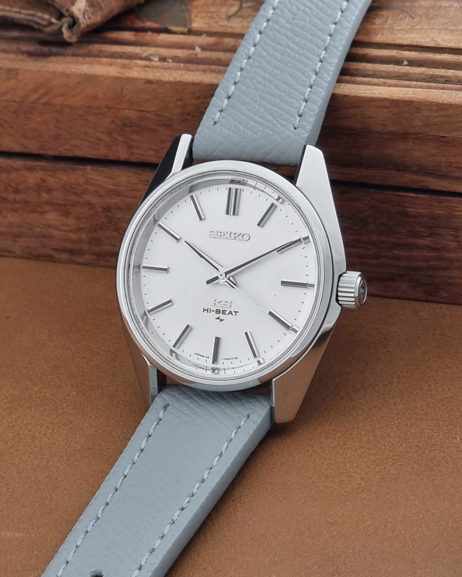 Vintage King Seiko 45-7001 watch with a grey leather strap on a brown background crown view