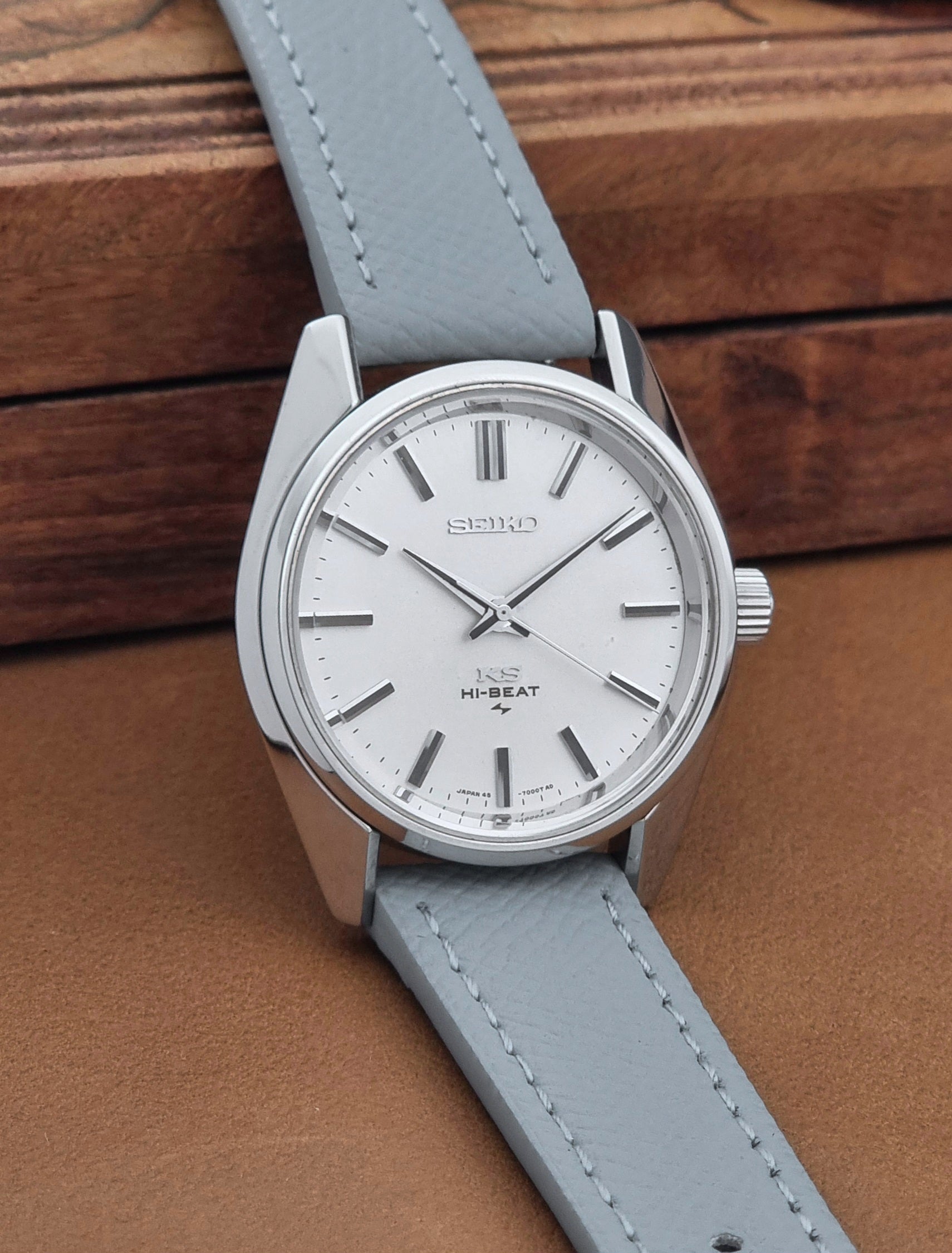 Vintage King Seiko 45-7001 watch with a grey leather strap on a brown background side view
