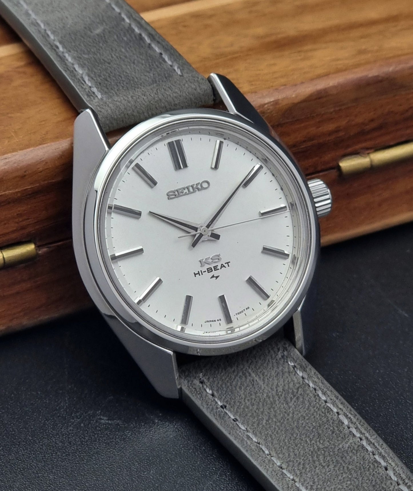 Vintage King Seiko watch with gray leather strap on a wooden surface