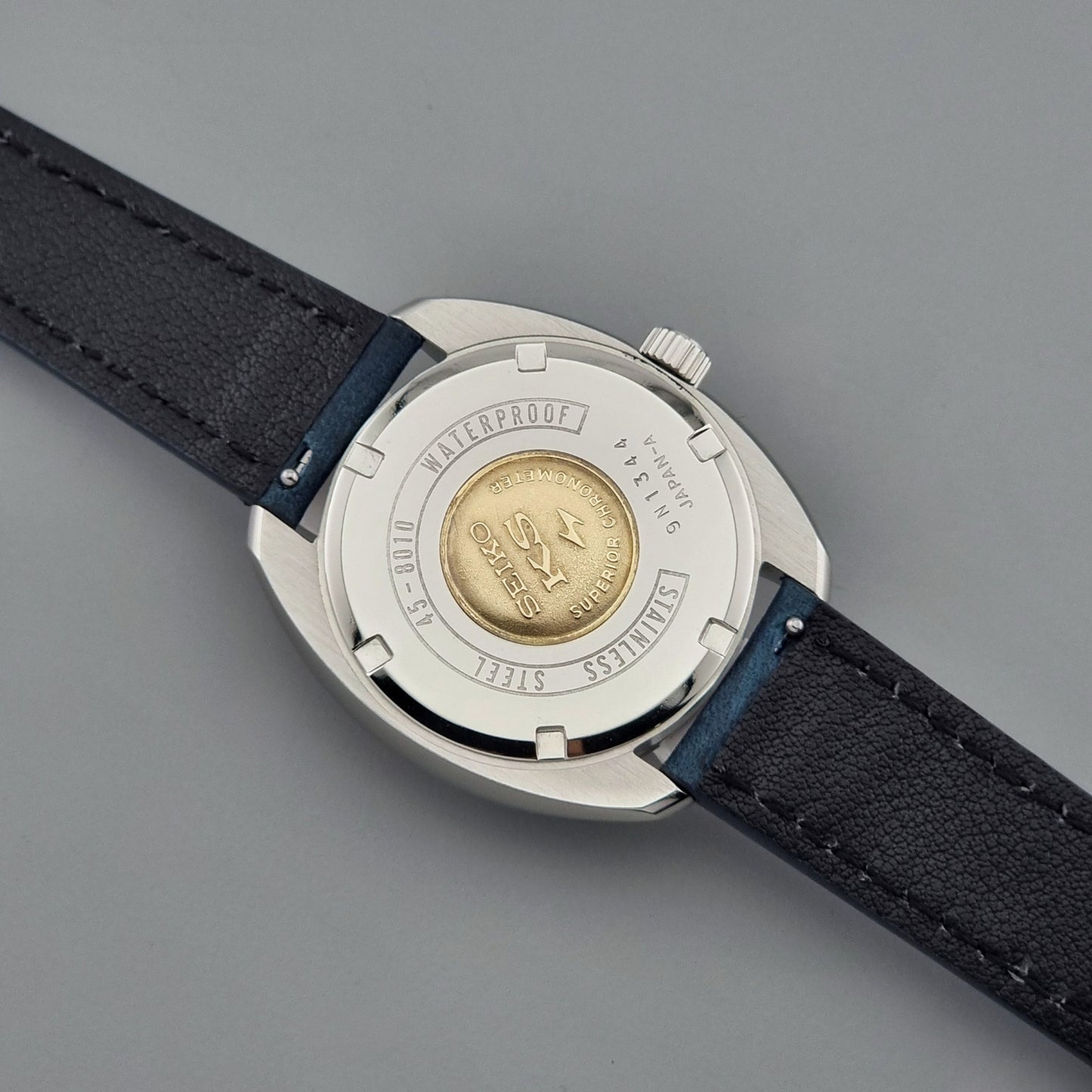 Vintage King Seiko Wristwatch case with black leather strap on a gray background