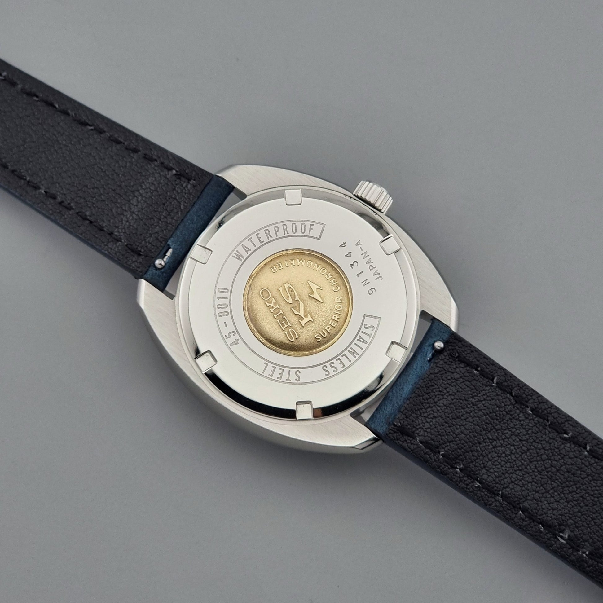 Vintage King Seiko Wristwatch case with black leather strap on a gray background