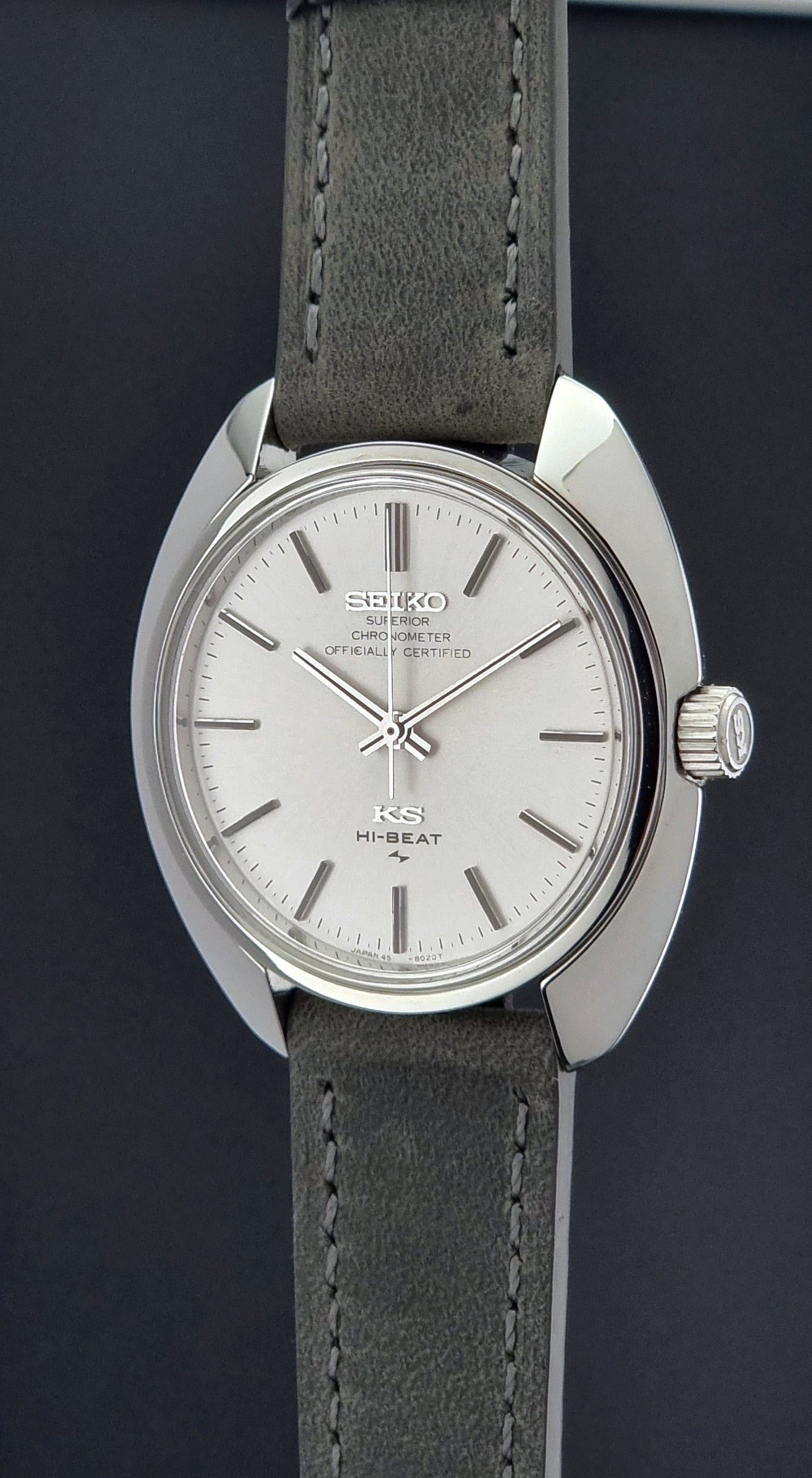 Vintage King Seiko 45-8010 Wristwatch with gray strap and silver case on a dark surface crown profile view