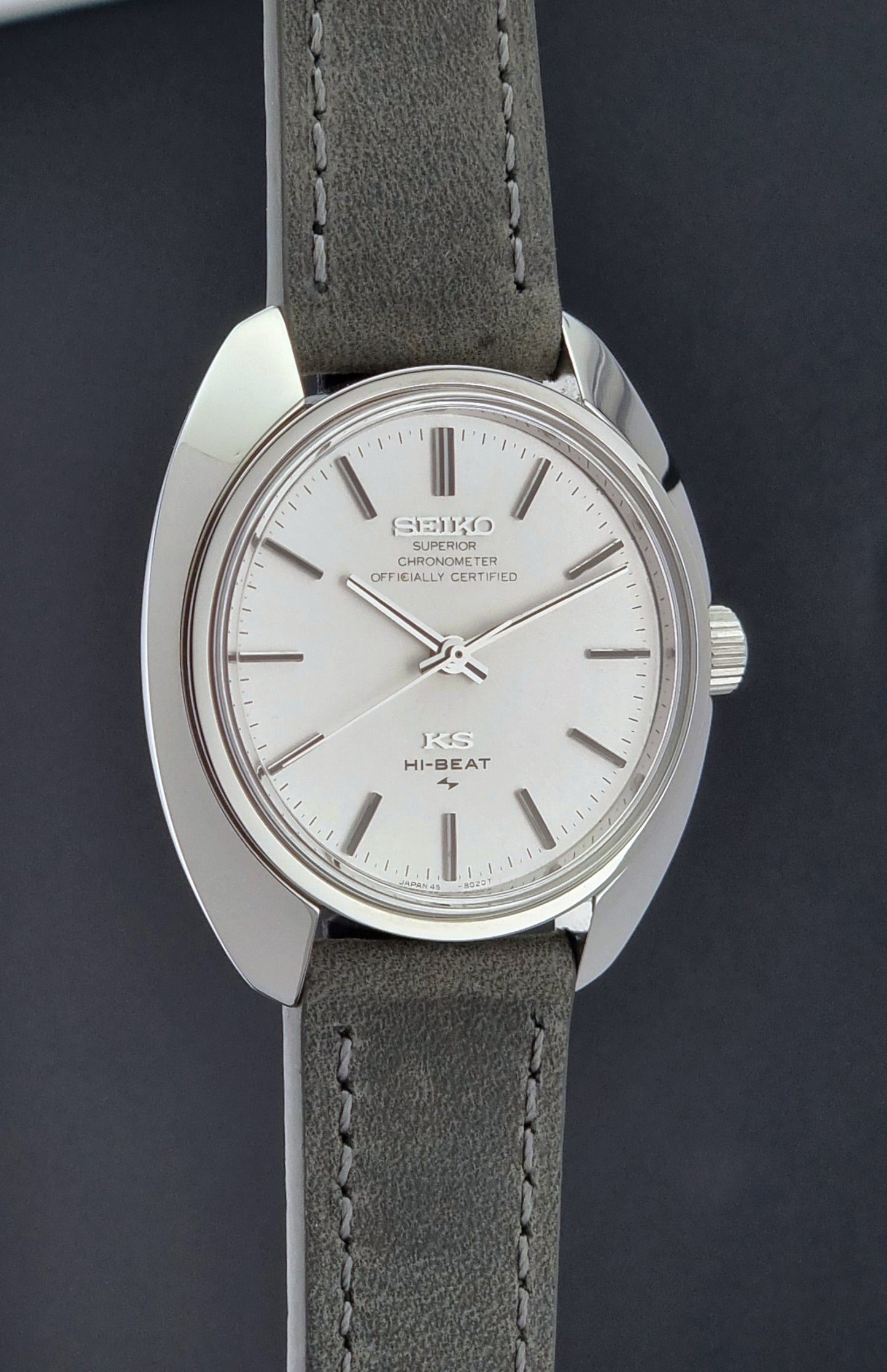 Vintage King Seiko 45-8010 Wristwatch with gray strap and silver case on a dark surface side profile view