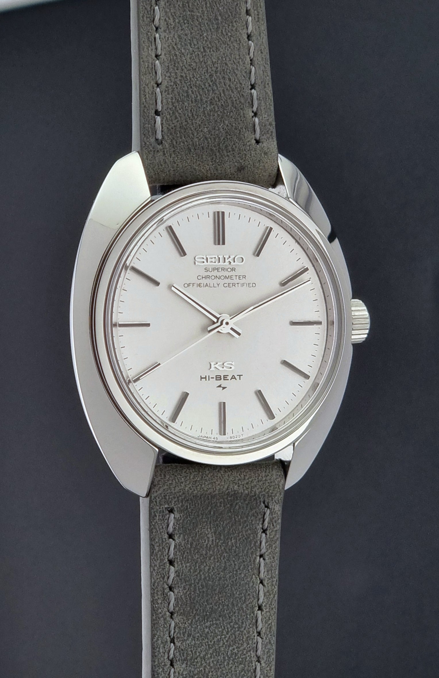 Vintage King Seiko 45-8010 Wristwatch with gray strap and silver case on a dark surface side profile view