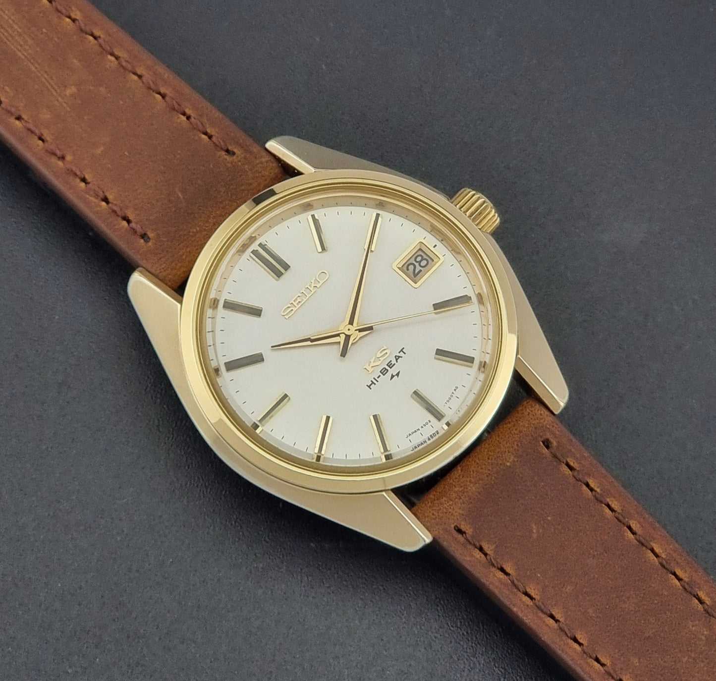 Vintage King Seiko 4502-7001 Wristwatch with brown leather strap on a dark surface close up dial view