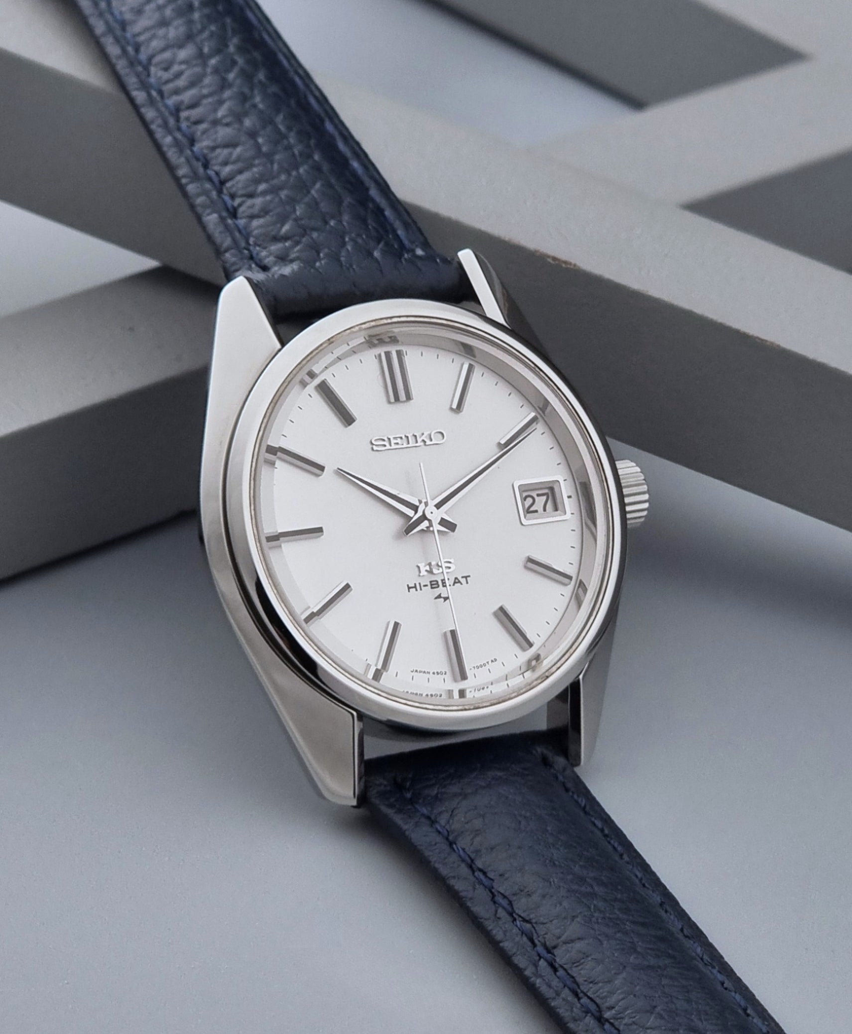 Vintage King Seiko 4502-7001 watch with a blue leather strap on a grey back ground side view