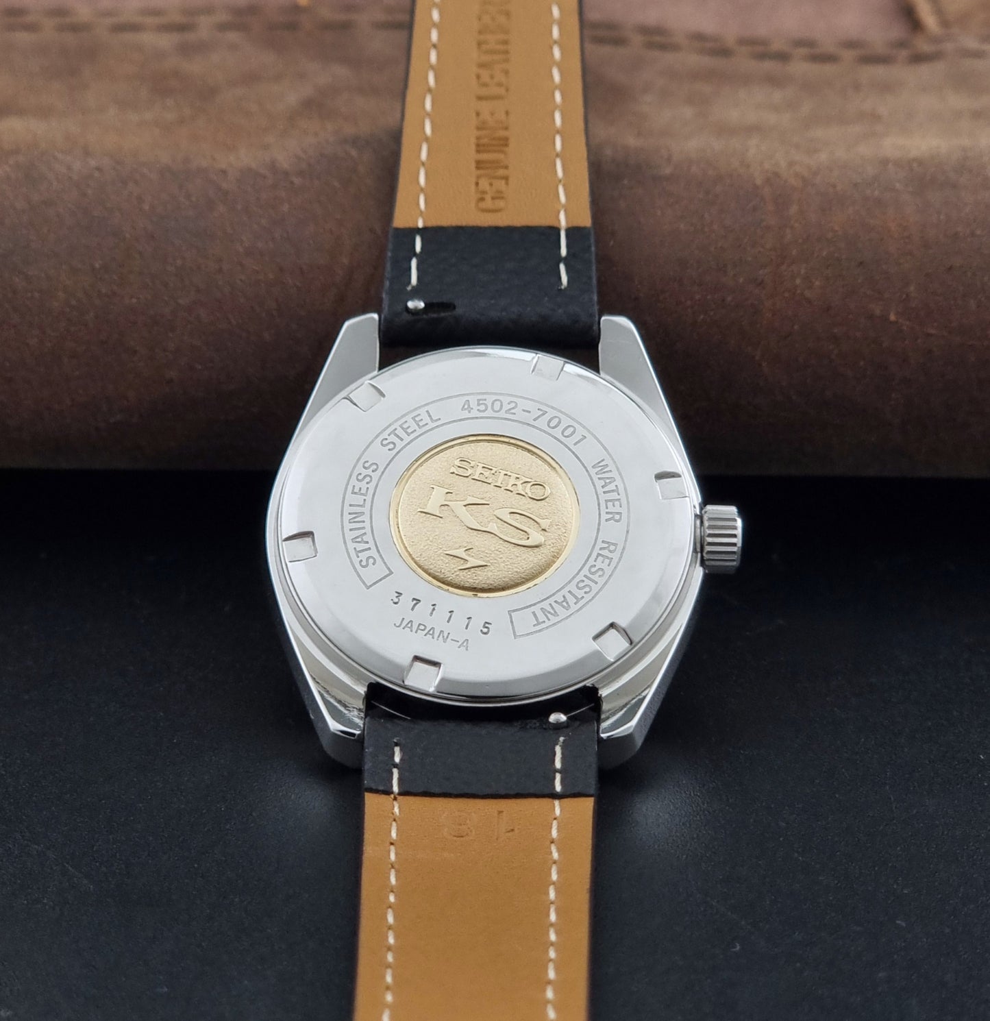 Vintage King Seiko 4502-7001 watch with black strap and silver case on a dark gray background case back view