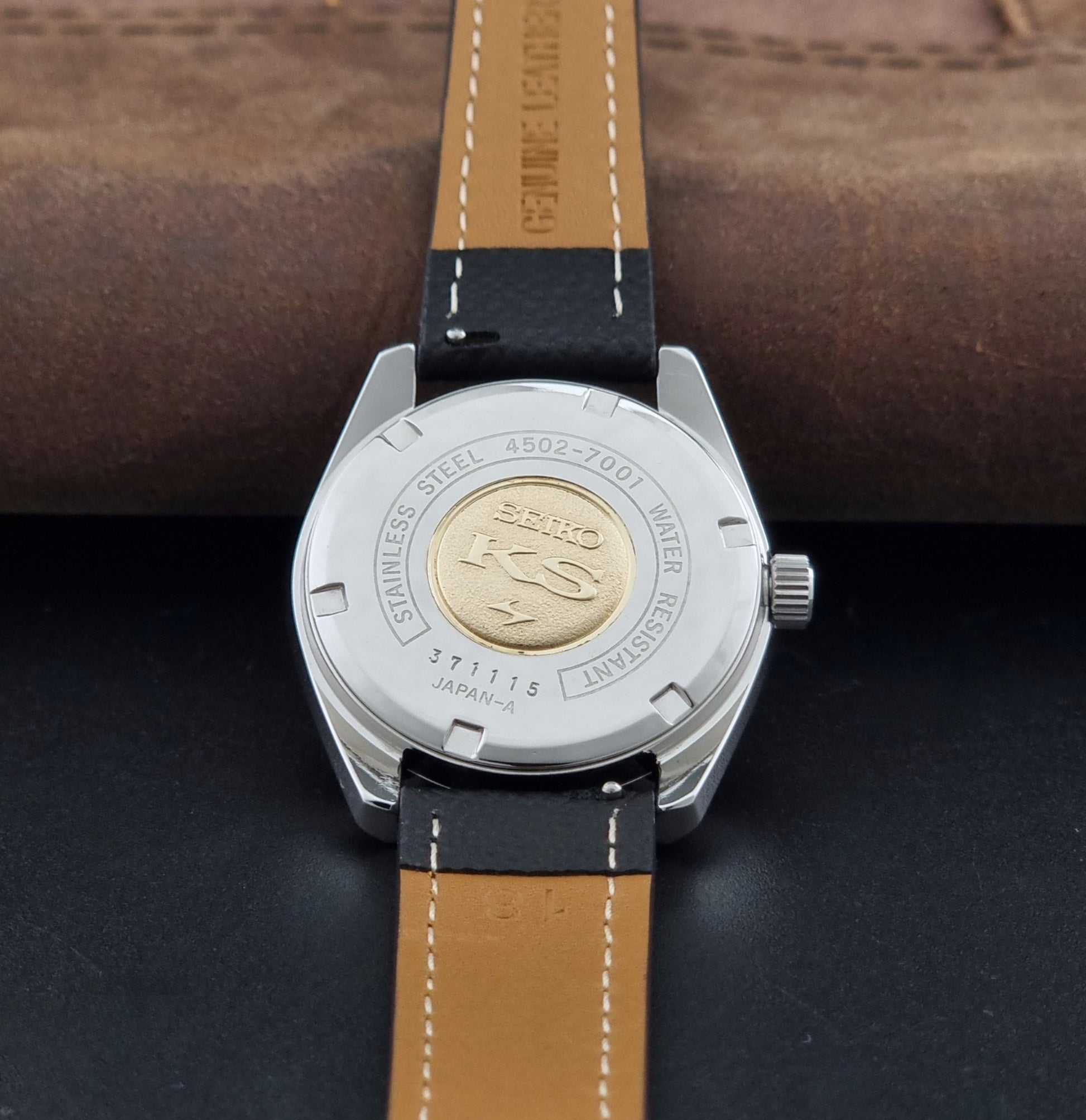 Vintage King Seiko 4502-7001 watch with black strap and silver case on a dark gray background case back view