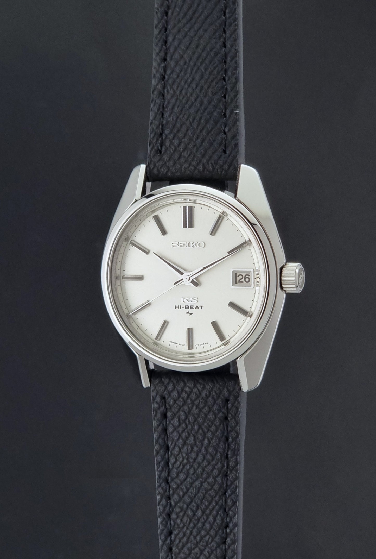 Vintage King Seiko 4502-7001 watch with black strap and silver case on a dark gray background crown profile view