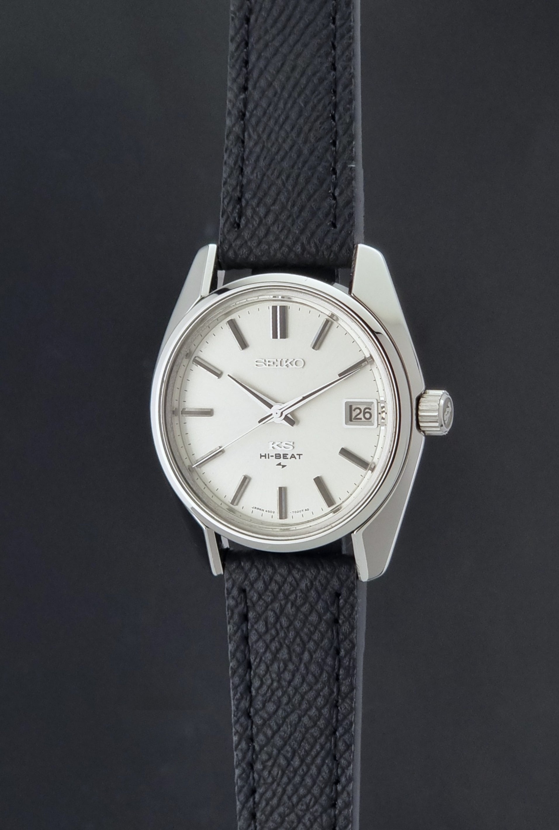 Vintage King Seiko 4502-7001 watch with black strap and silver case on a dark gray background crown profile view
