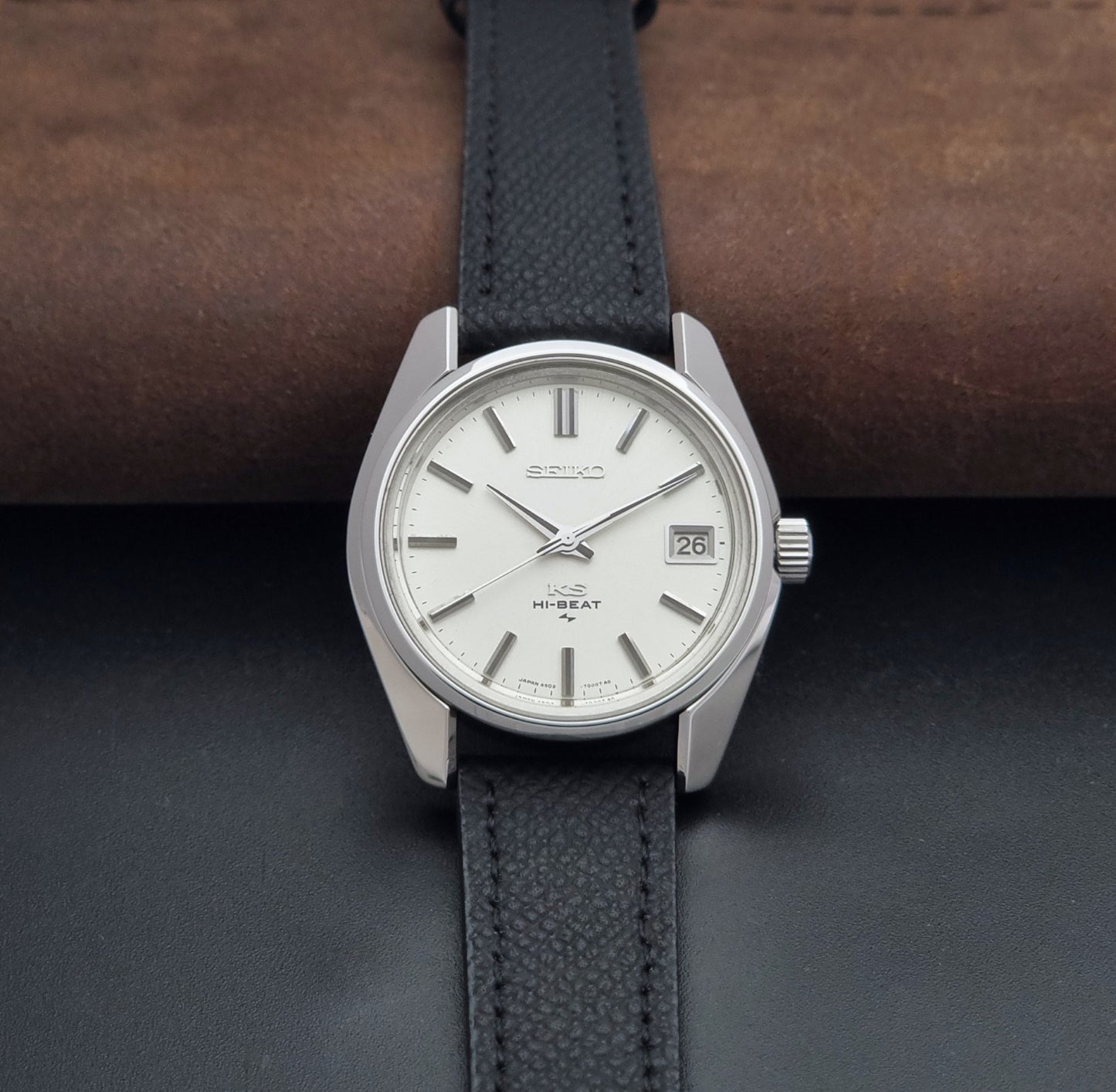 Vintage King Seiko 4502-7001 watch with black strap and silver case on a dark gray background dial view