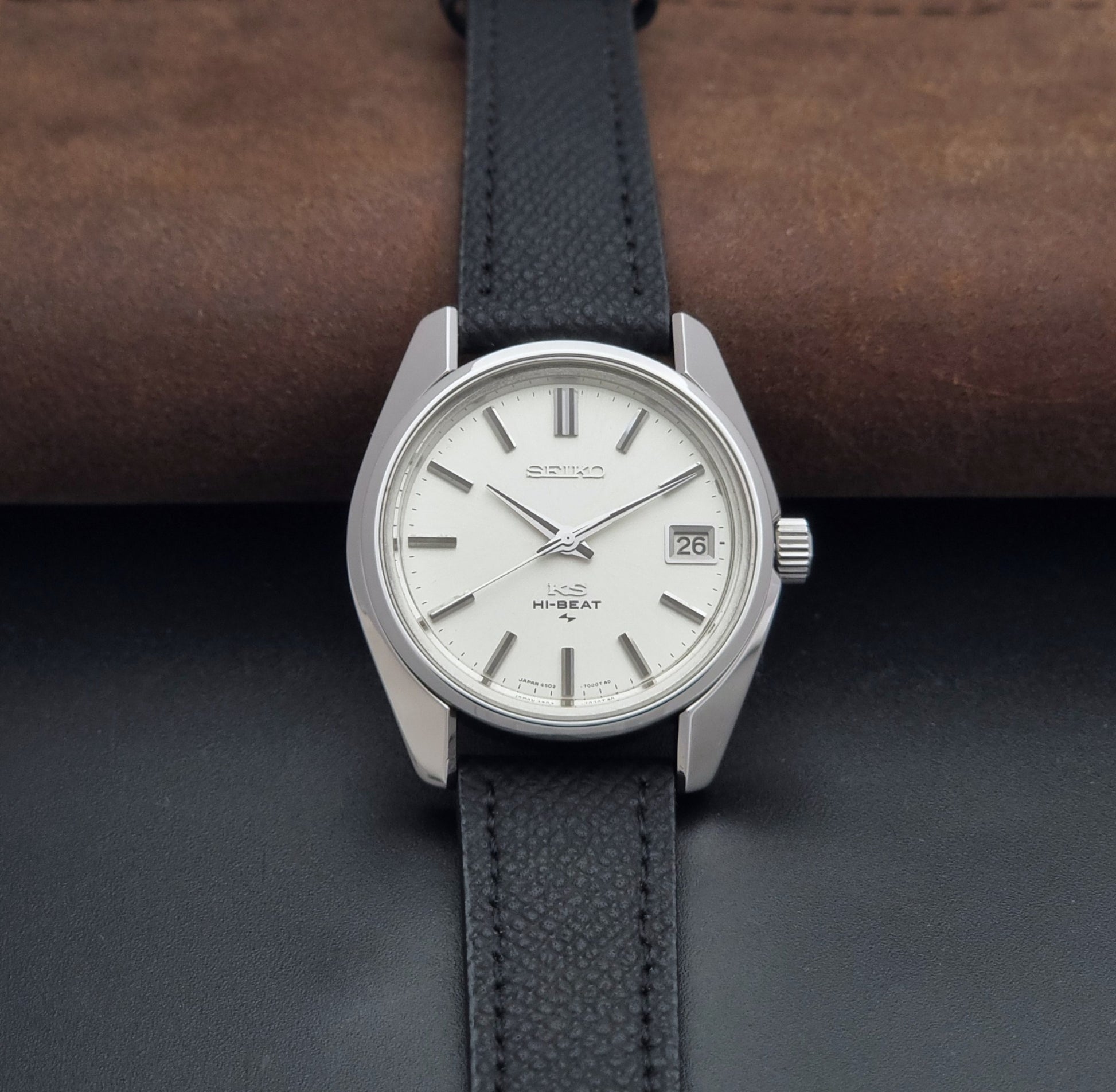 Vintage King Seiko 4502-7001 watch with black strap and silver case on a dark gray background dial view