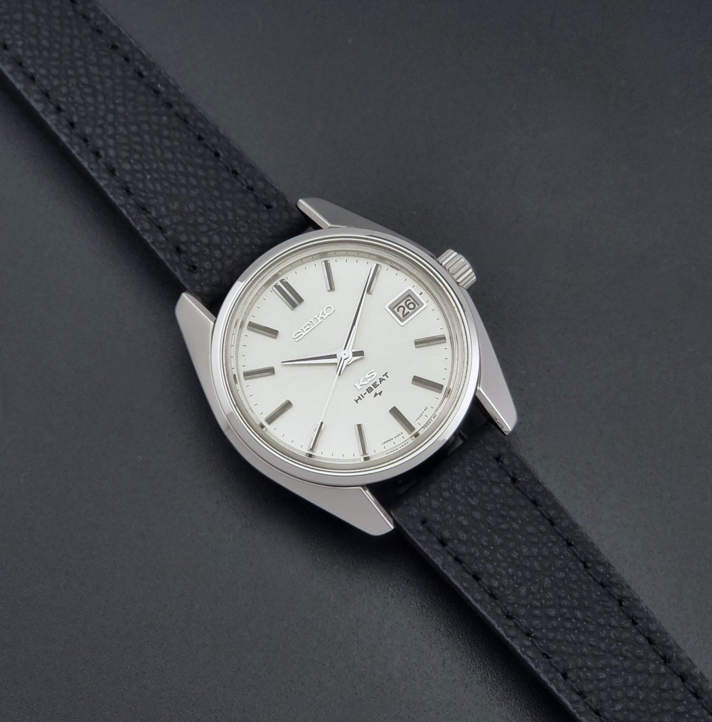 Vintage King Seiko 4502-7001 watch with black strap and silver case on a dark gray background close up dial view