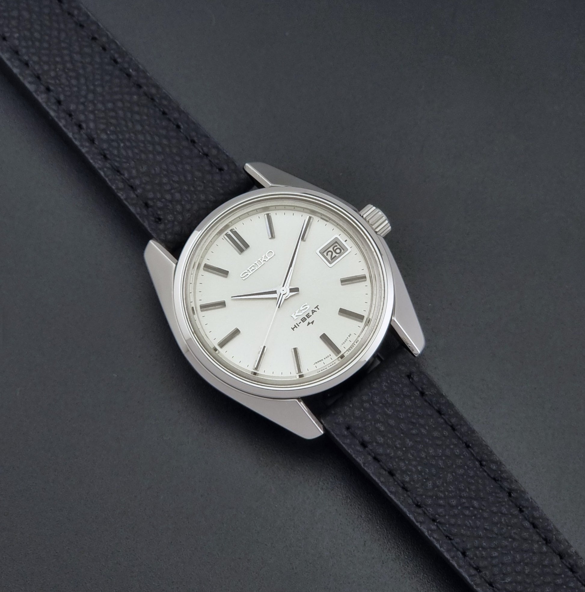 Vintage King Seiko 4502-7001 watch with black strap and silver case on a dark gray background close up dial view