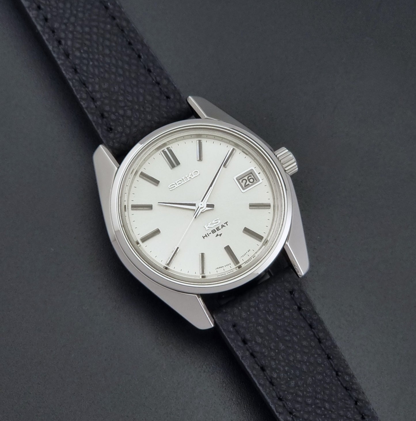 Vintage King Seiko 4502-7001 watch with black strap and silver case on a dark gray background front view