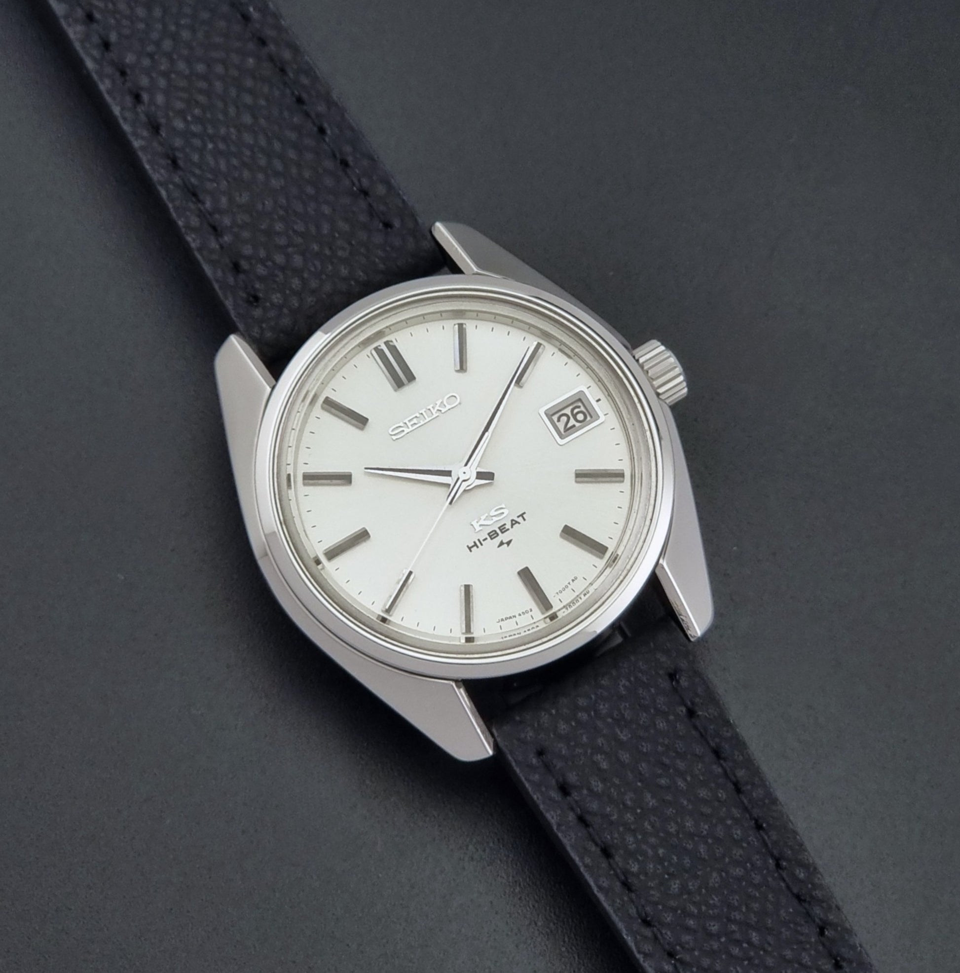 Vintage King Seiko 4502-7001 watch with black strap and silver case on a dark gray background front view