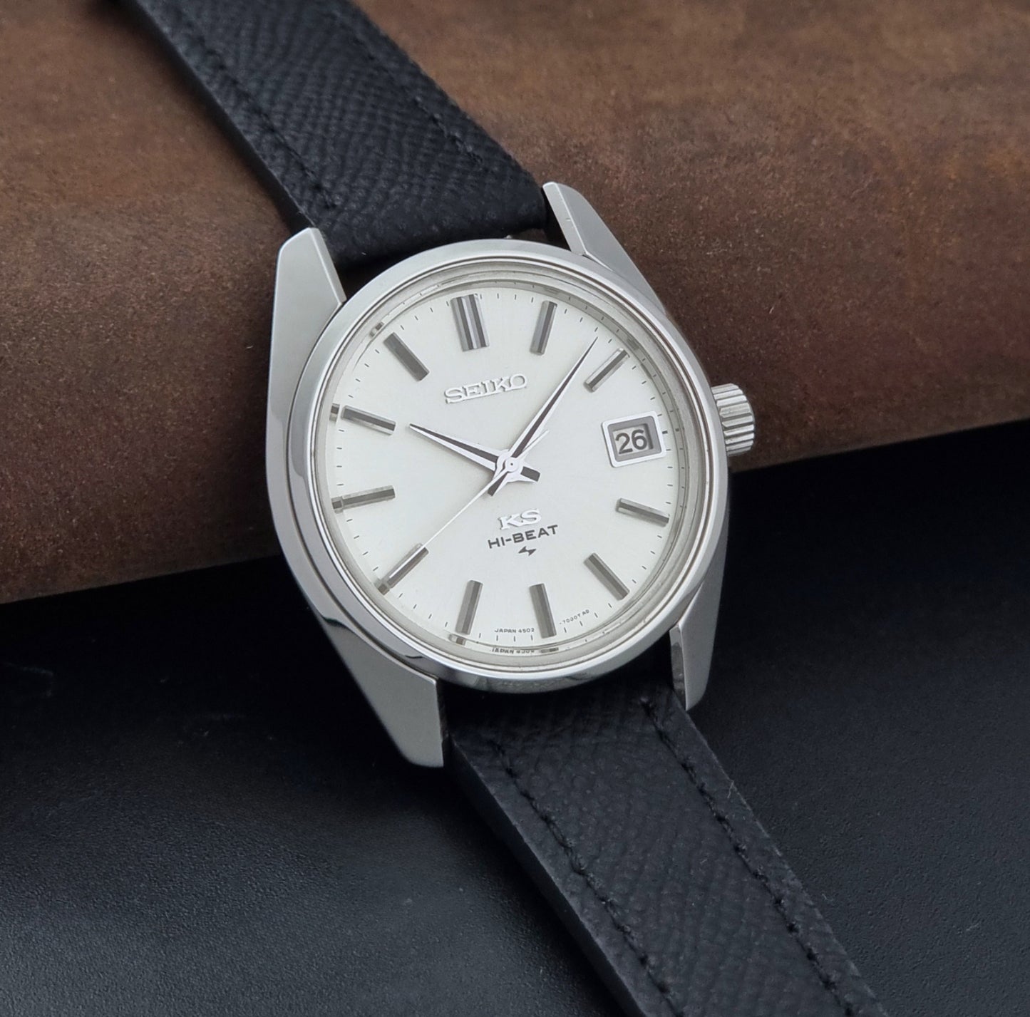 Vintage King Seiko 4502-7001 watch with black strap and silver case on a dark gray background side view