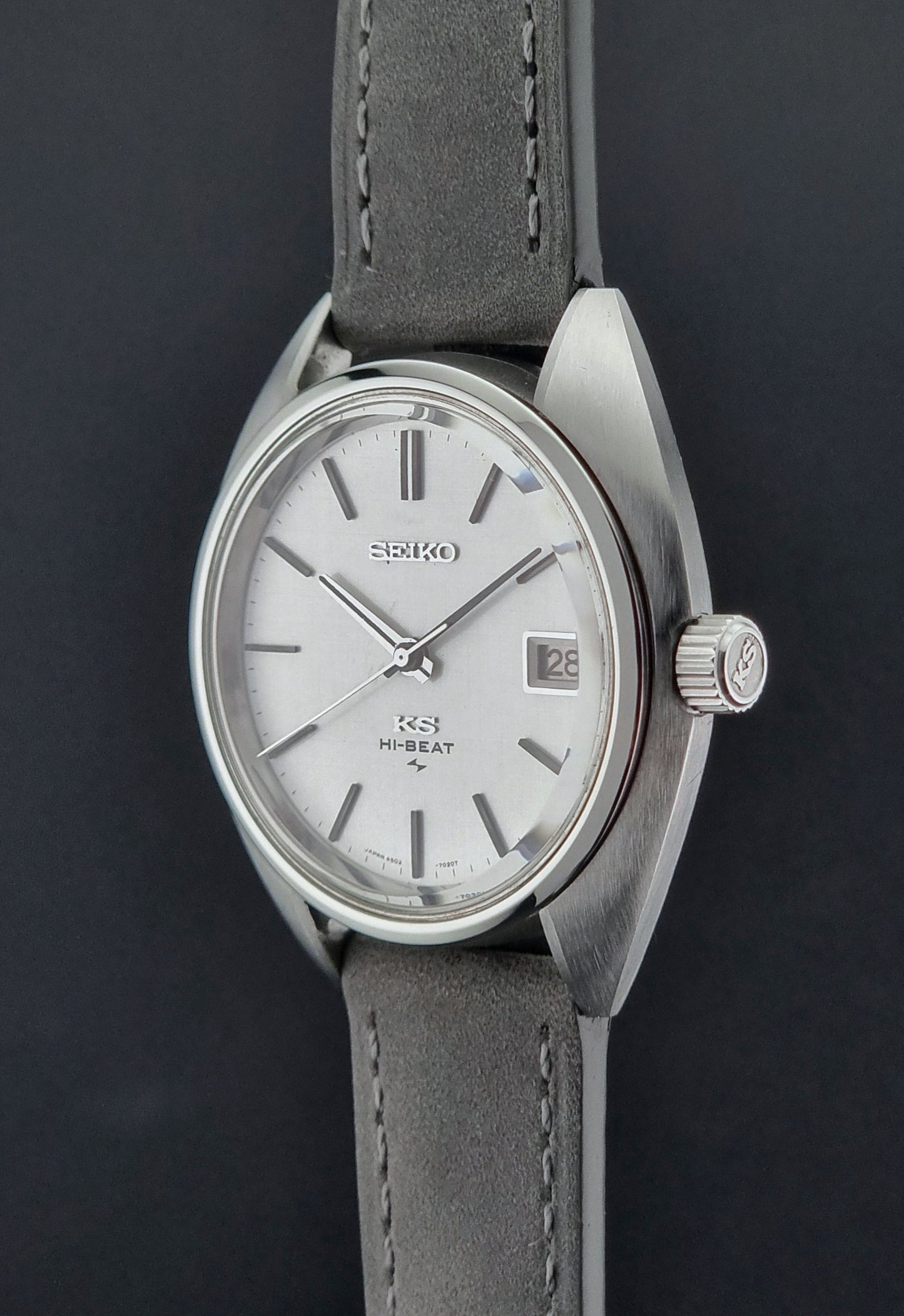 Vintage King Seiko Wristwatch 4502-7010 with gray strap and silver case on a dark surface crown profile view