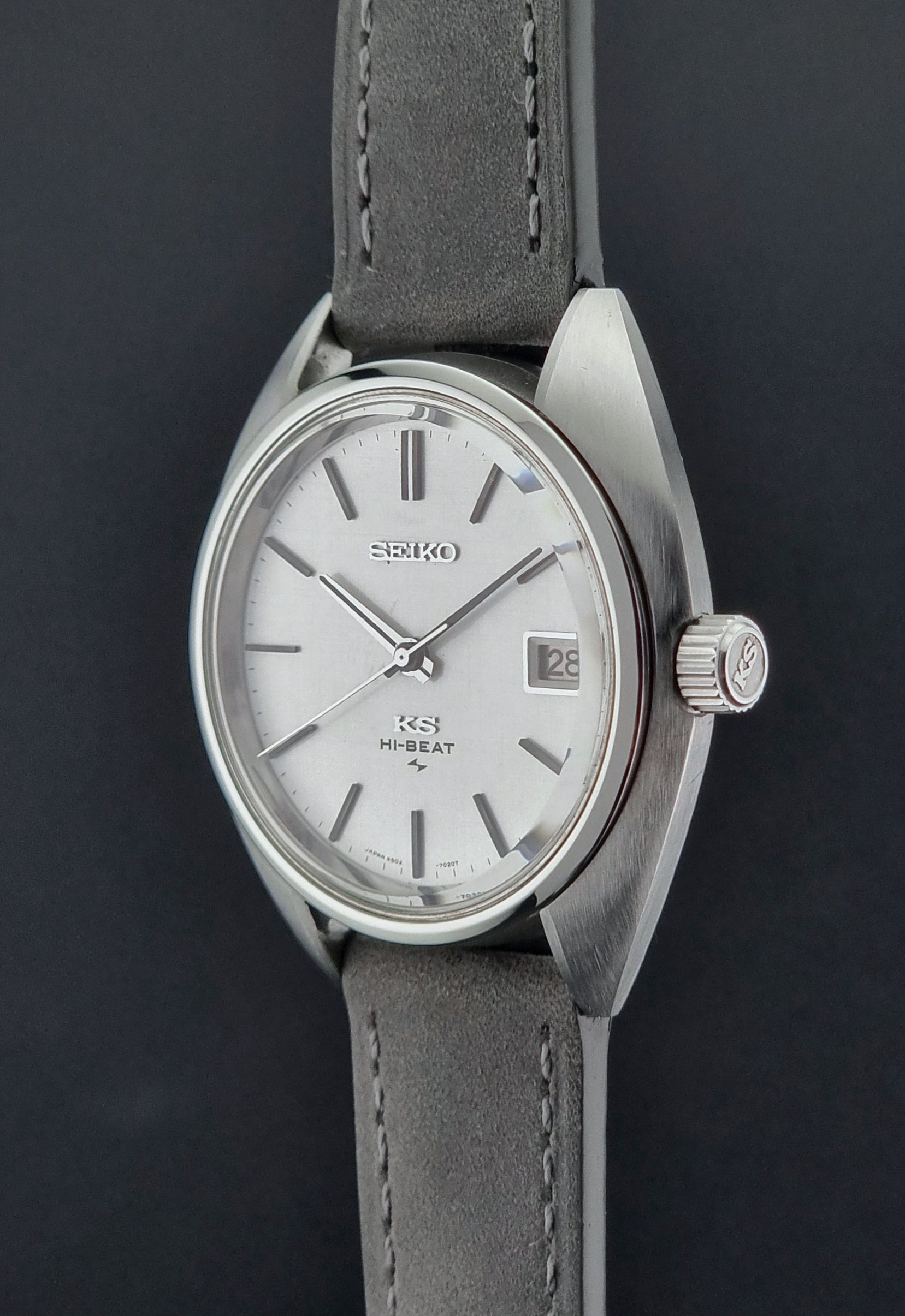 Vintage King Seiko Wristwatch 4502-7010 with gray strap and silver case on a dark surface crown profile view