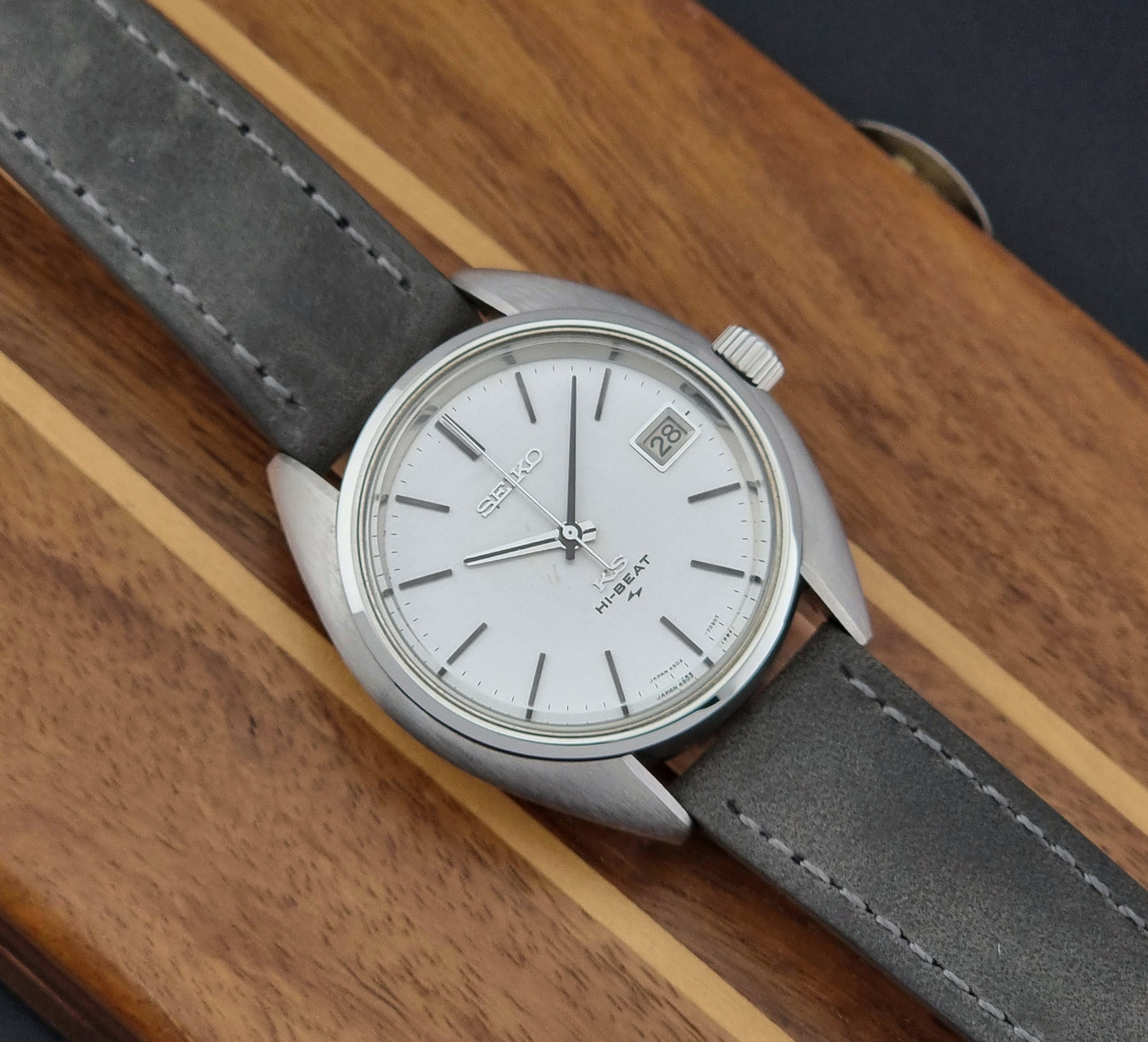 Vintage King Seiko Wristwatch 4502-7010 with gray strap and silver case on a wooden surface