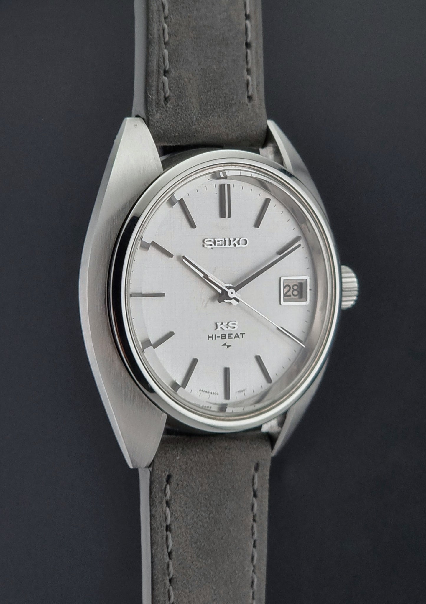 Vintage King Seiko Wristwatch 4502-7010 with gray strap and silver case on a dark surface side profile view