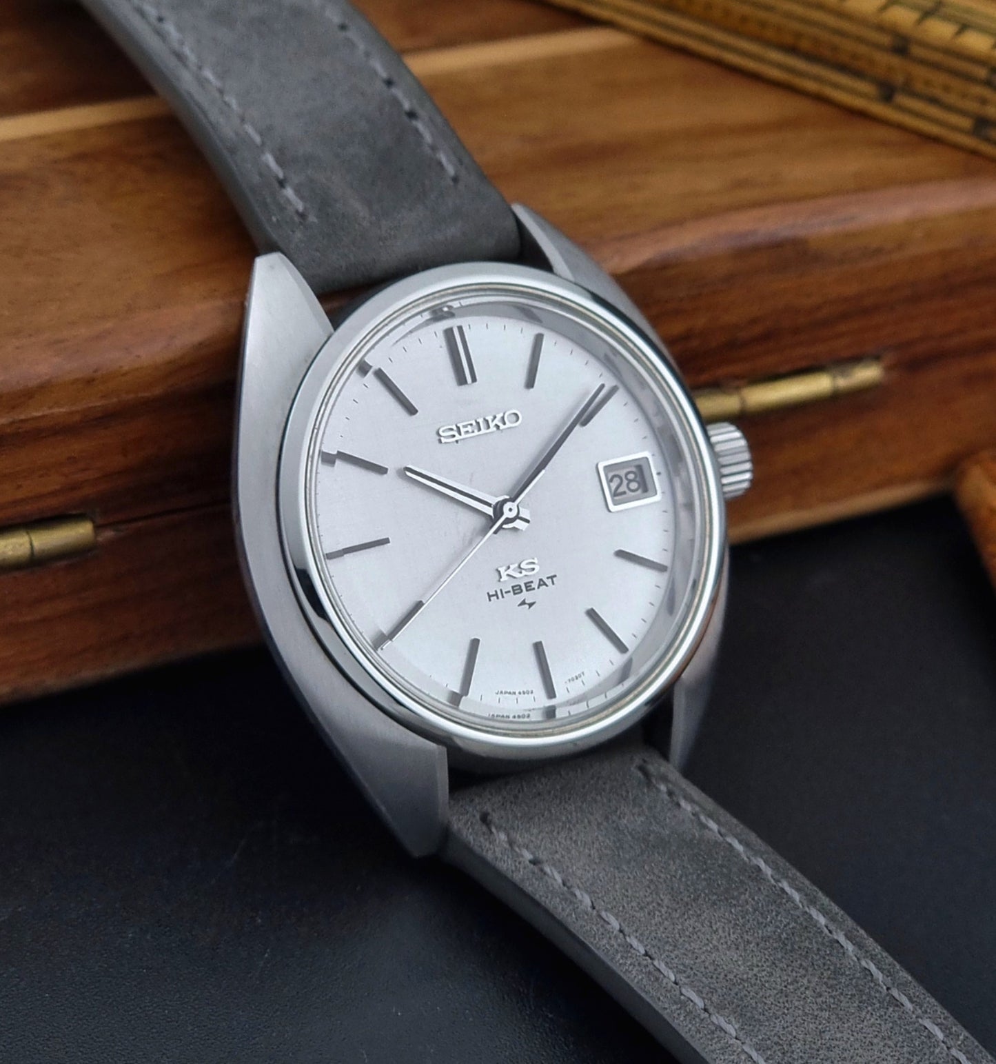 Vintage King Seiko Wristwatch 4502-7010 with gray strap and silver case on a wooden surface side view