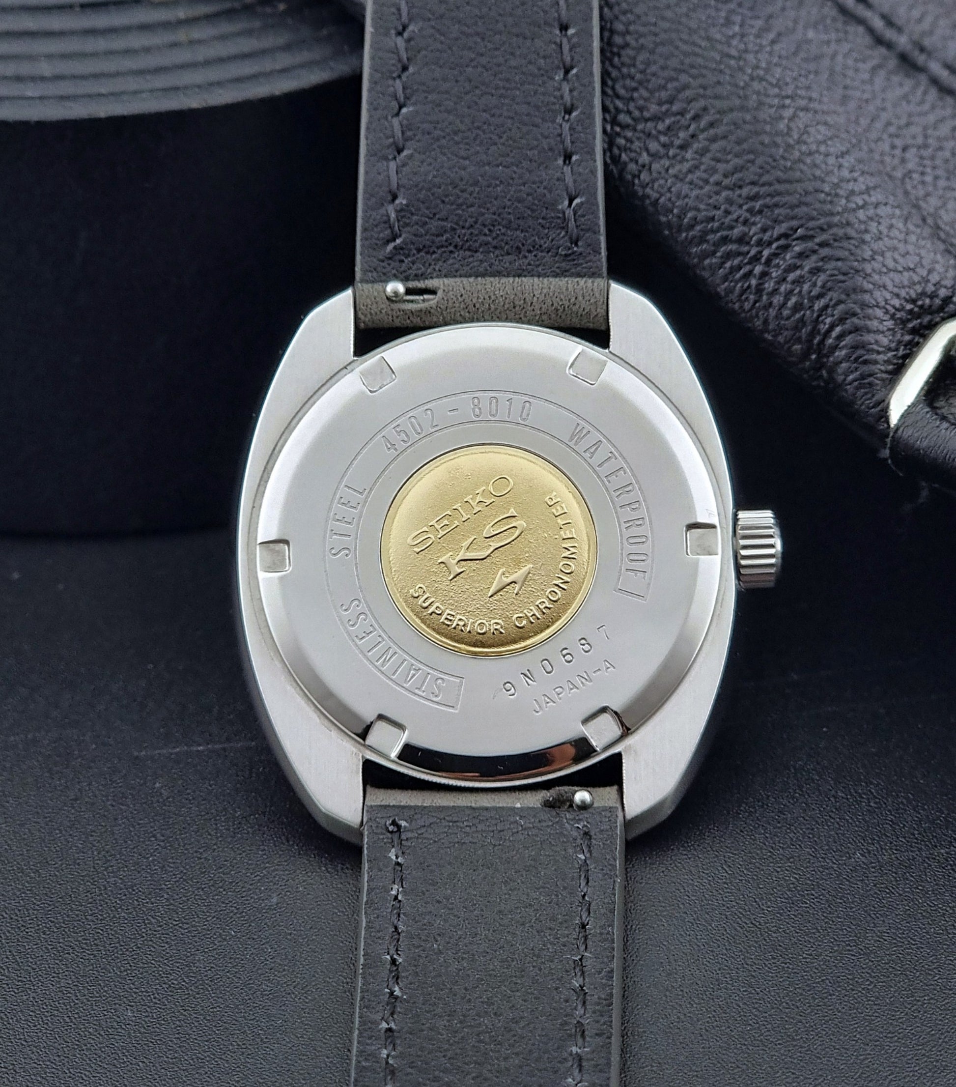 King Seiko Watch Hi-Beat 4502-8010 with gray strap and silver dial on a dark background case back with a gold medallion showing the Seiko KS logo