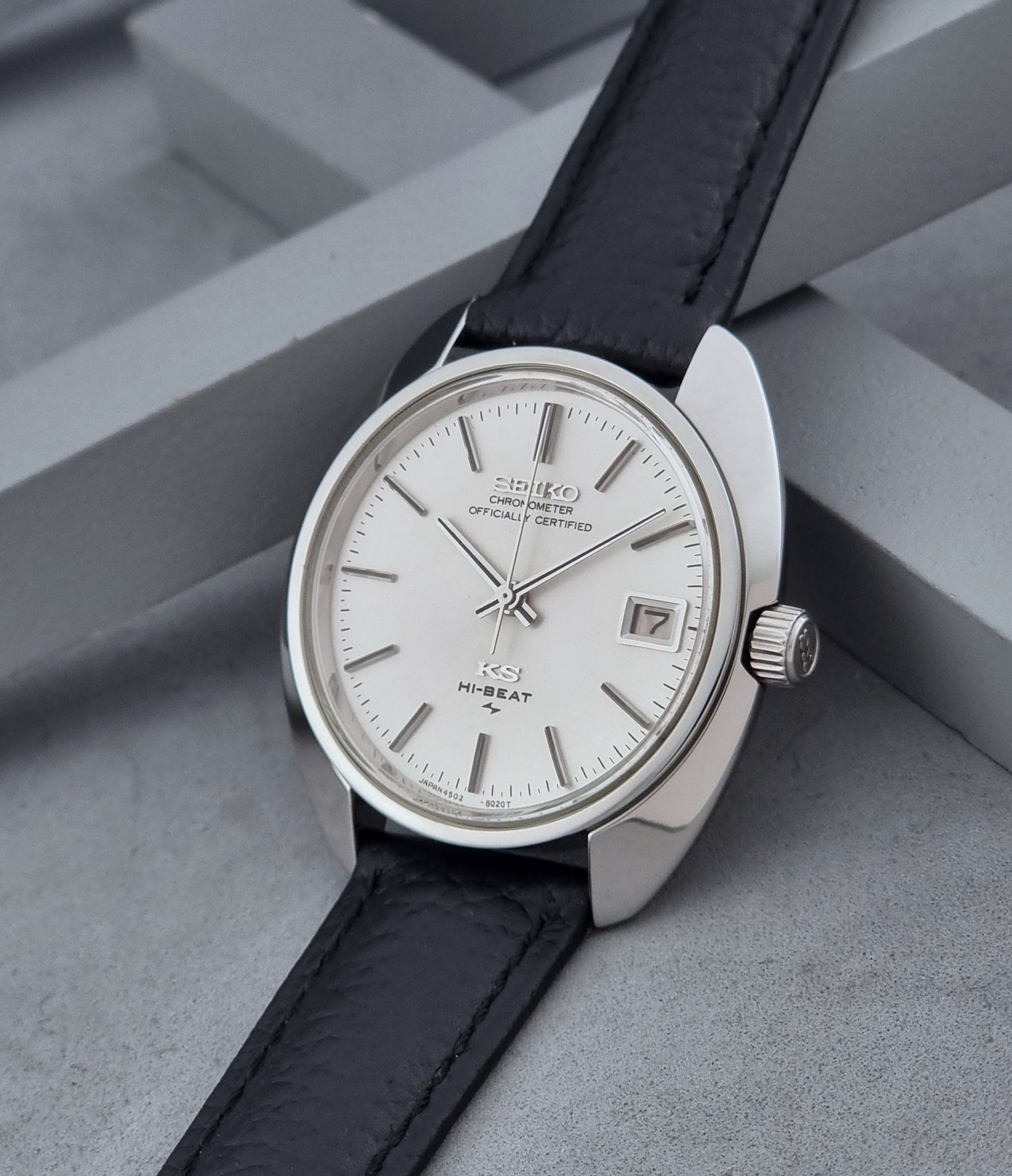 Vintage King Seiko Wristwatch 4502-8010 with black leather strap on a gray background crown view