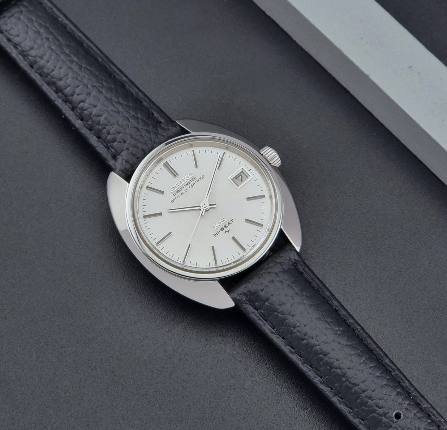 Vintage King Seiko Wristwatch 4502-8010 with black leather strap on a gray background dial