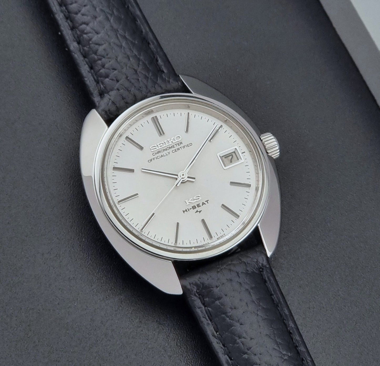 Vintage King Seiko Wristwatch 4502-8010 with black leather strap on a gray background front view