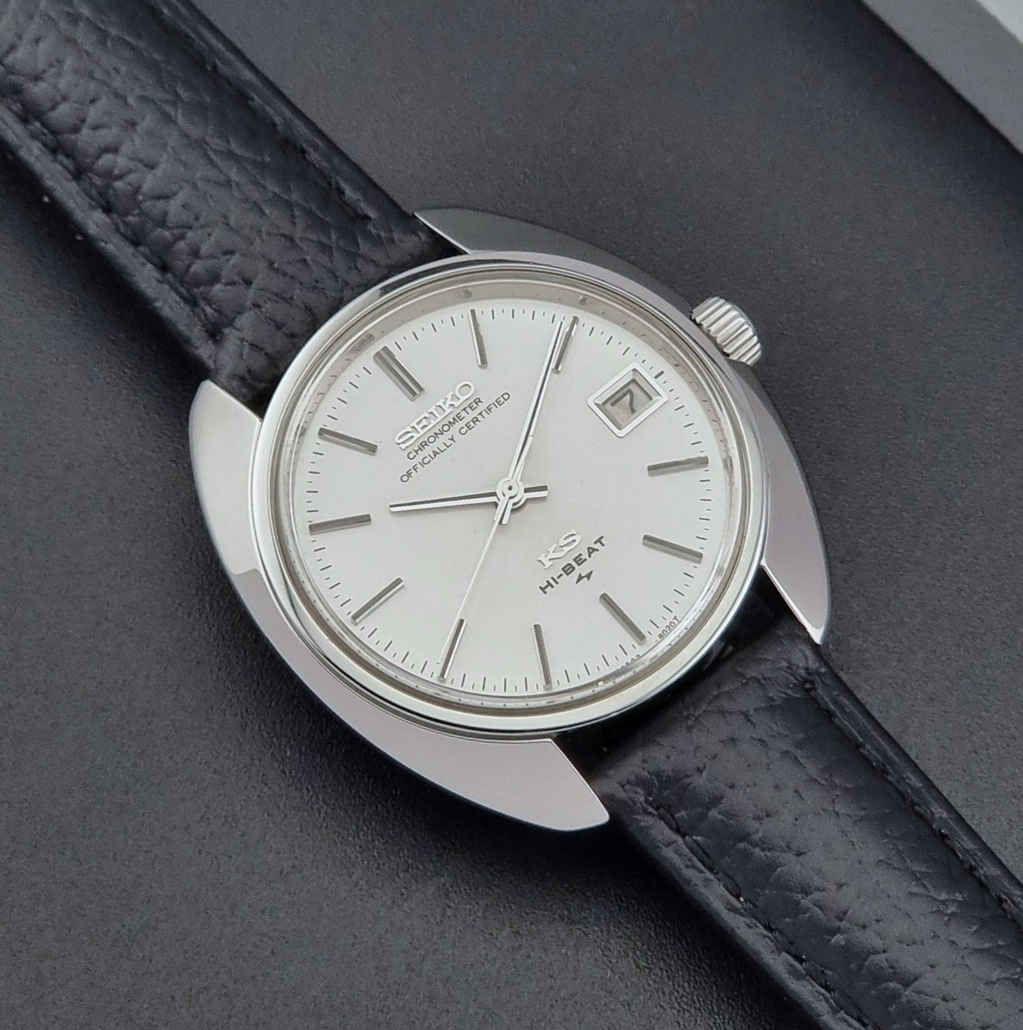 Vintage King Seiko Wristwatch 4502-8010 with black leather strap on a gray background close up dial view