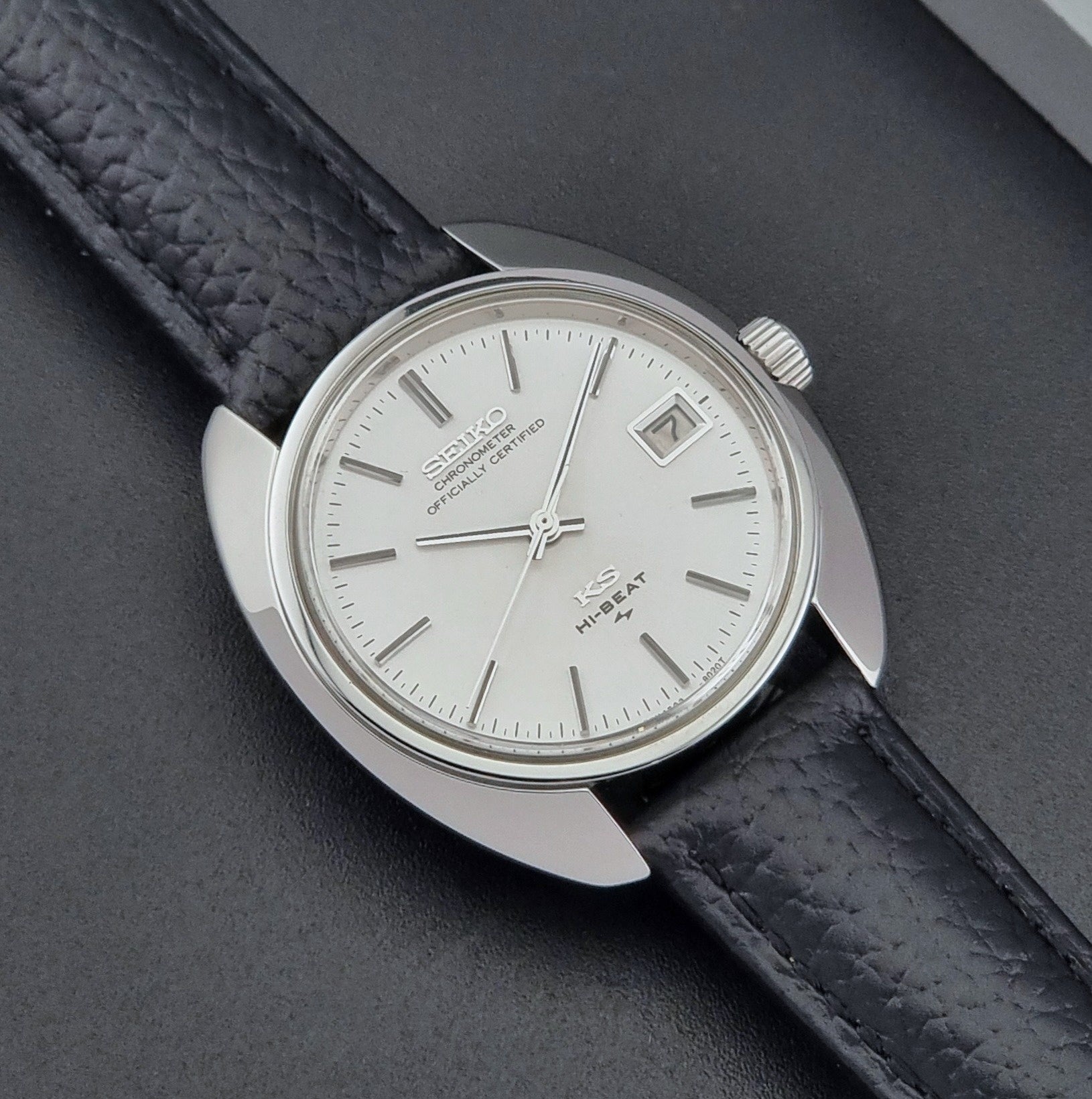 Vintage King Seiko Wristwatch 4502-8010 with black leather strap on a gray background close up dial view