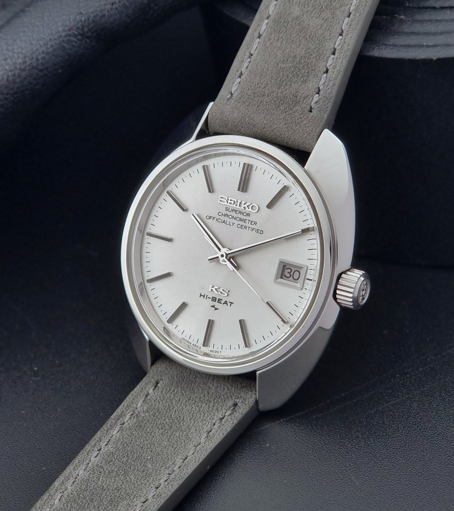 King Seiko Watch Hi-Beat 4502-8010 with gray strap and silver dial on a dark background crown side view