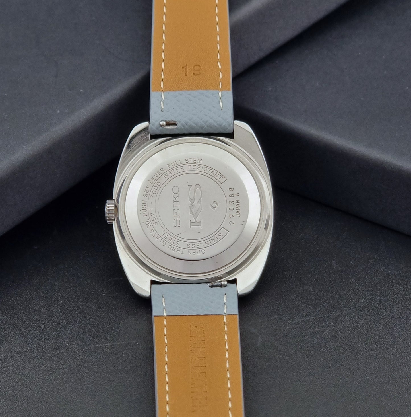 Vintage King Seiko Wristwatch 5621-7000 with light grey leather strap on a dark gray background case back view